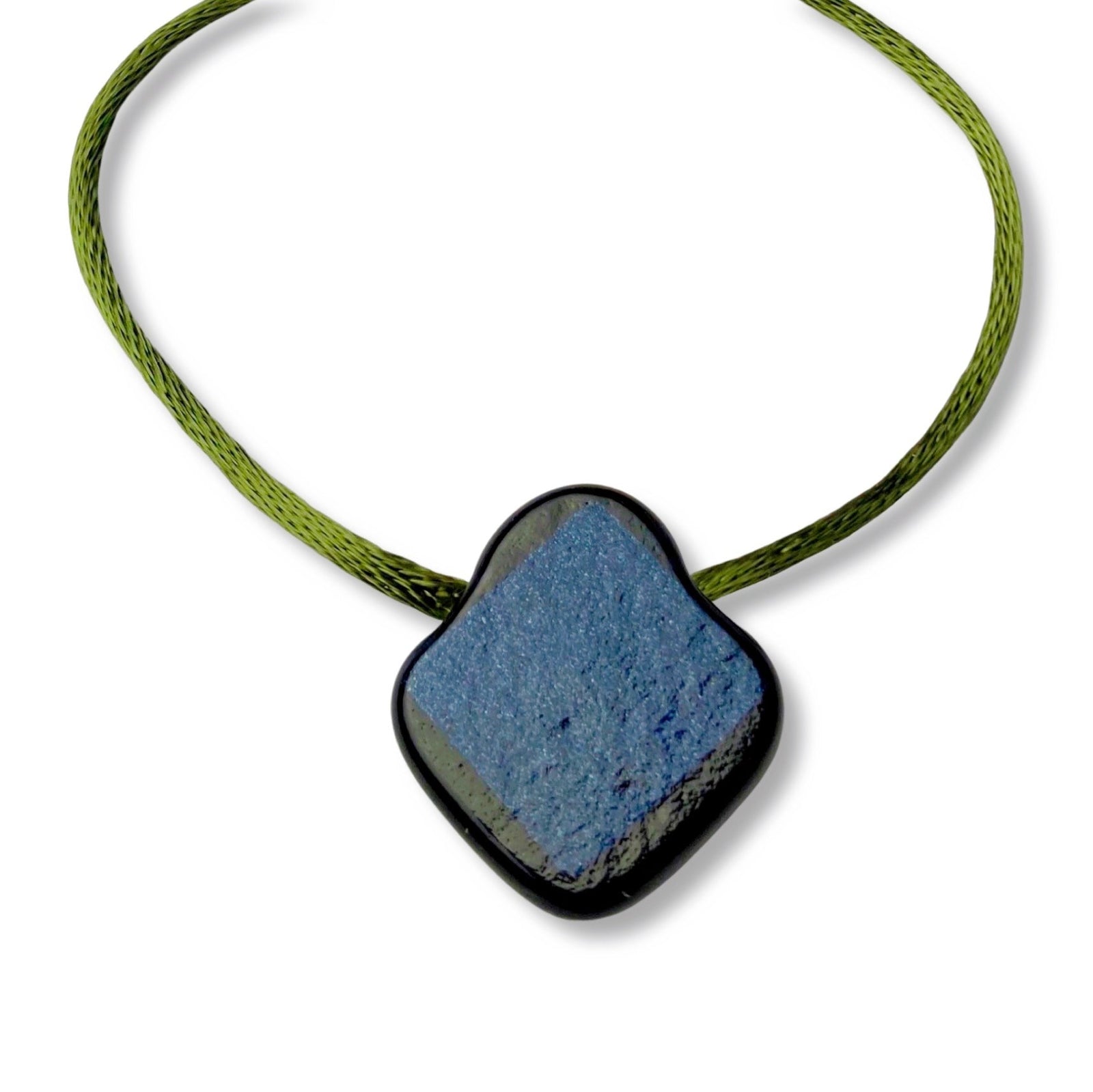 Backside of glass pendant, blue square surrounded with black, on green cord against a white background.