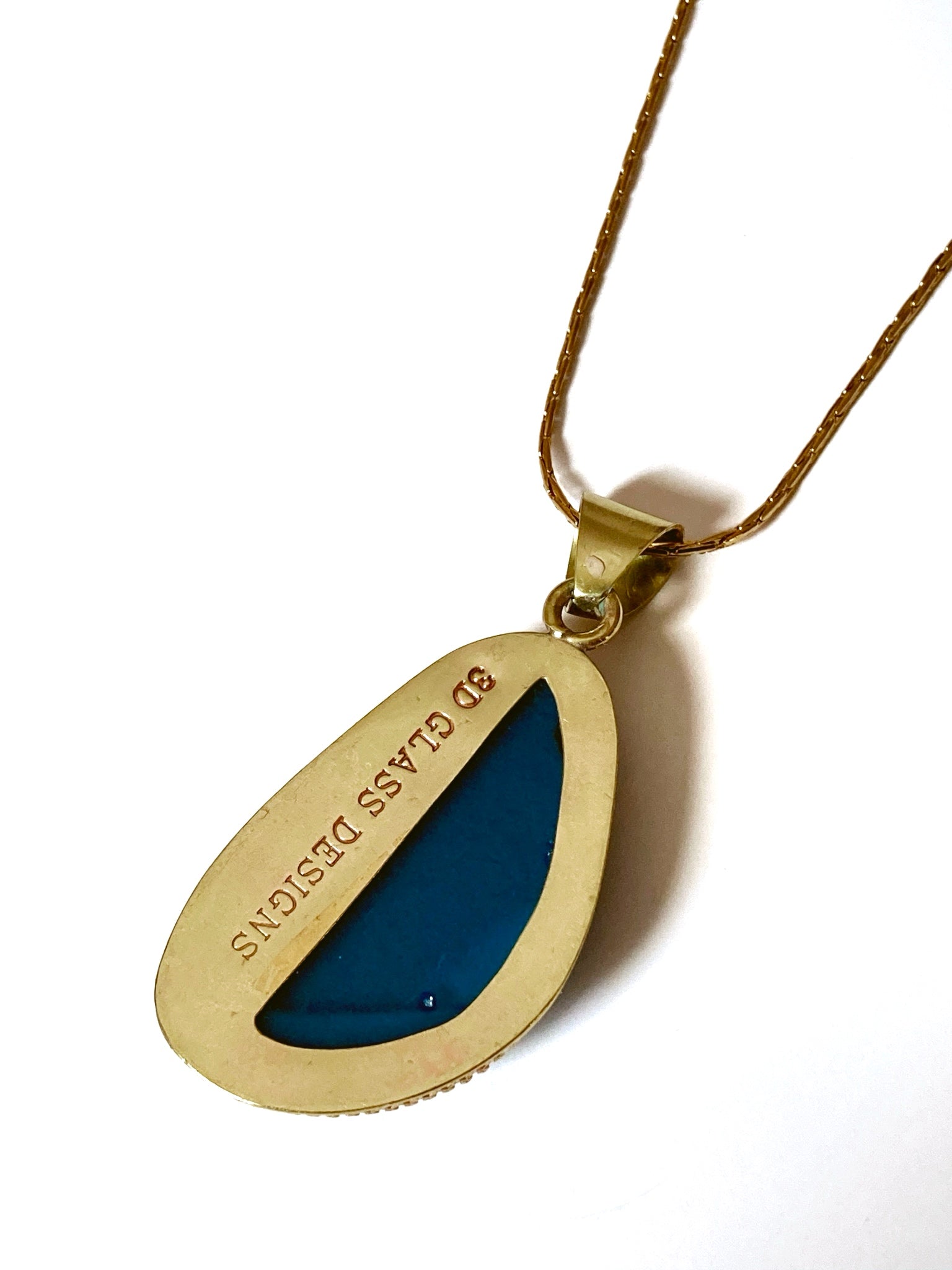 Backside of handmade fused glass and brass pendant.