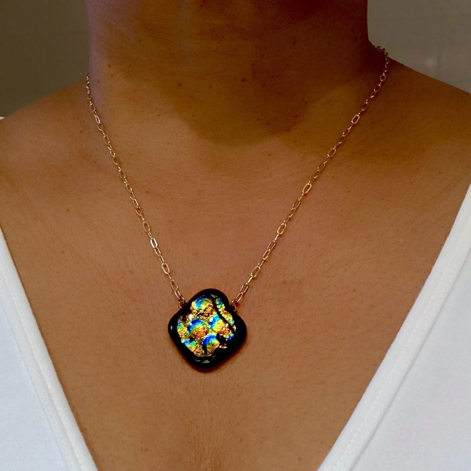 Model wearing dichroic glass pendant with a delicate gold chain, by 3D Glass Designs.