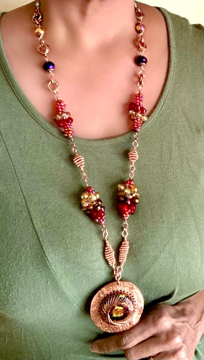 Model wearing long copper and dichroic glass pendant necklace with handmade bead clusters, by 3D Glass Designs.