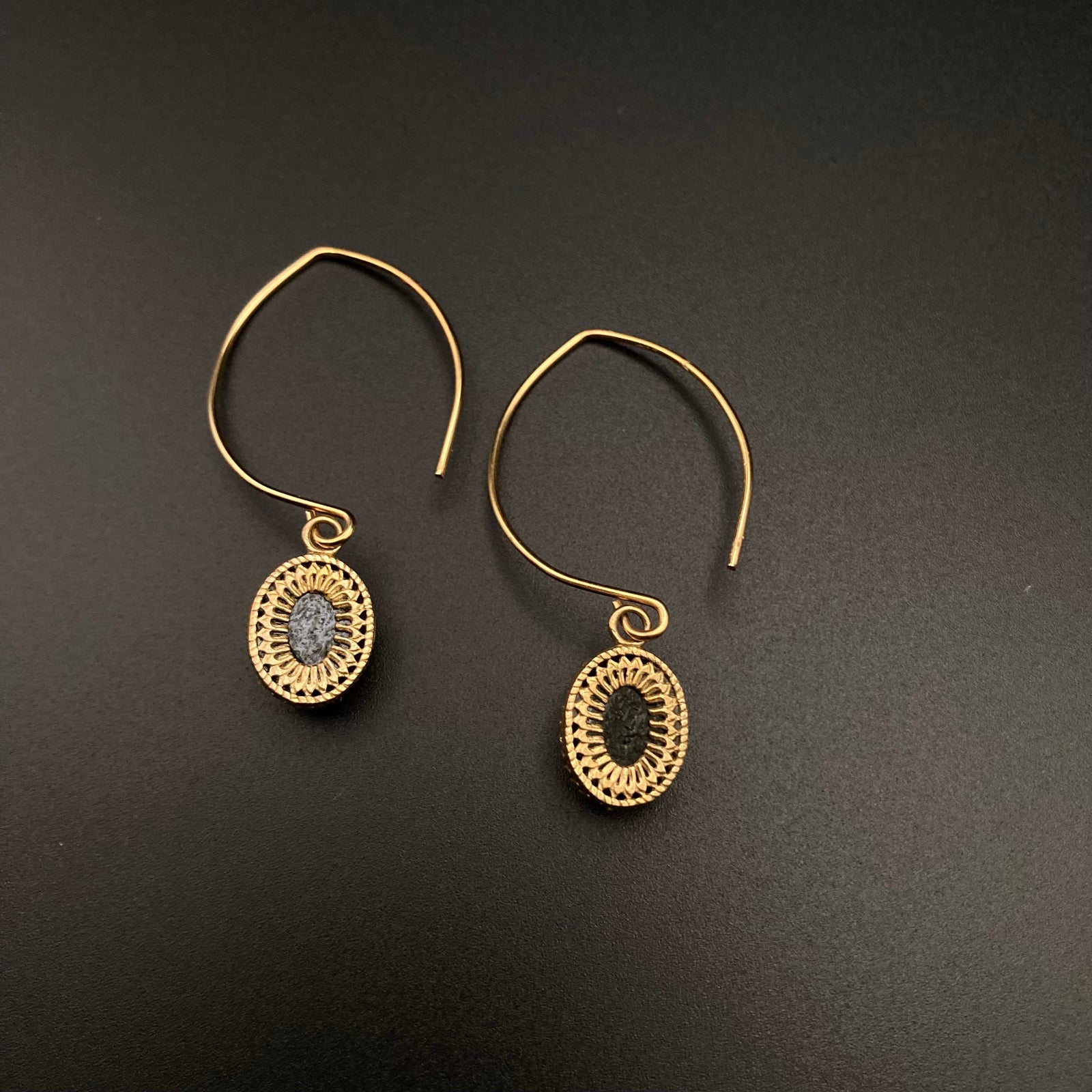Backside of a pair of glass earrings set in brass with gold ear wires against a grey background, by3D Glass Designs.