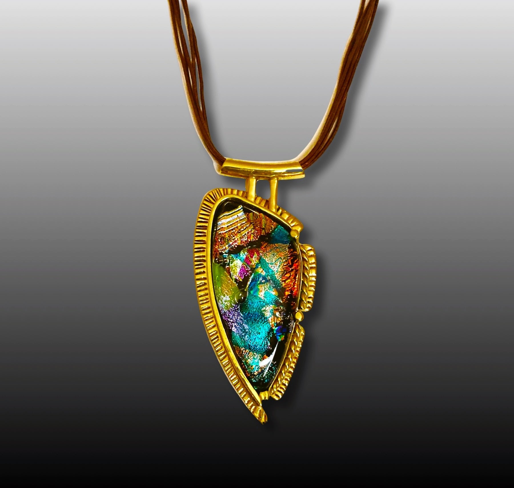Handcrafted brass pendant featuring multicolored dichroic glass in a shield-shape hung on a multistrand leather necklace, by 3D Glass Designs.