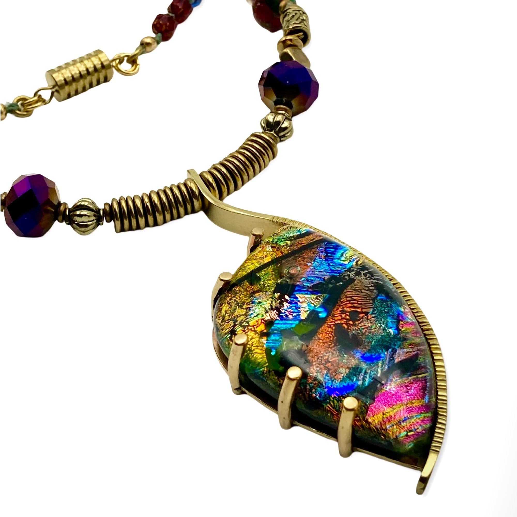 Dichroic glass set in a unique brass pendant, with prongs on left side and a textured bezel on the right side. Pendant is hung on a 29" long hand-knotted multicolor beaded necklace, by 3D Glass Designs.