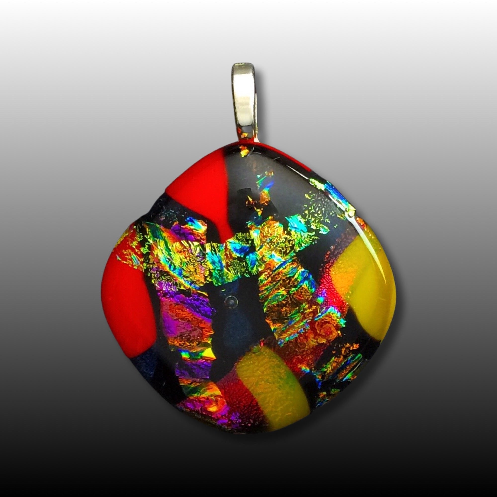 Colorful dichroic fused glass pendant in red, blue, yellow, purple, green and gold colors with a black satin cord. By 3D Glass Designs.