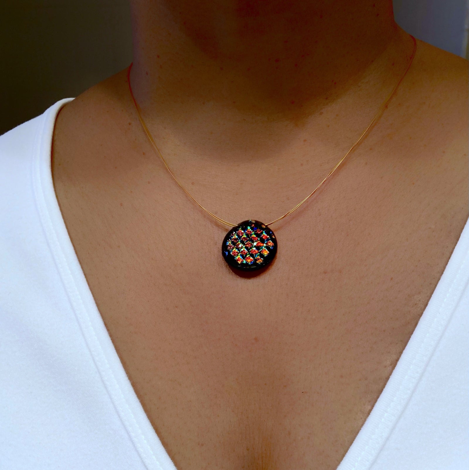 Model wearing round multi-color dichroic glass pendant, by 3D Glass Designs.