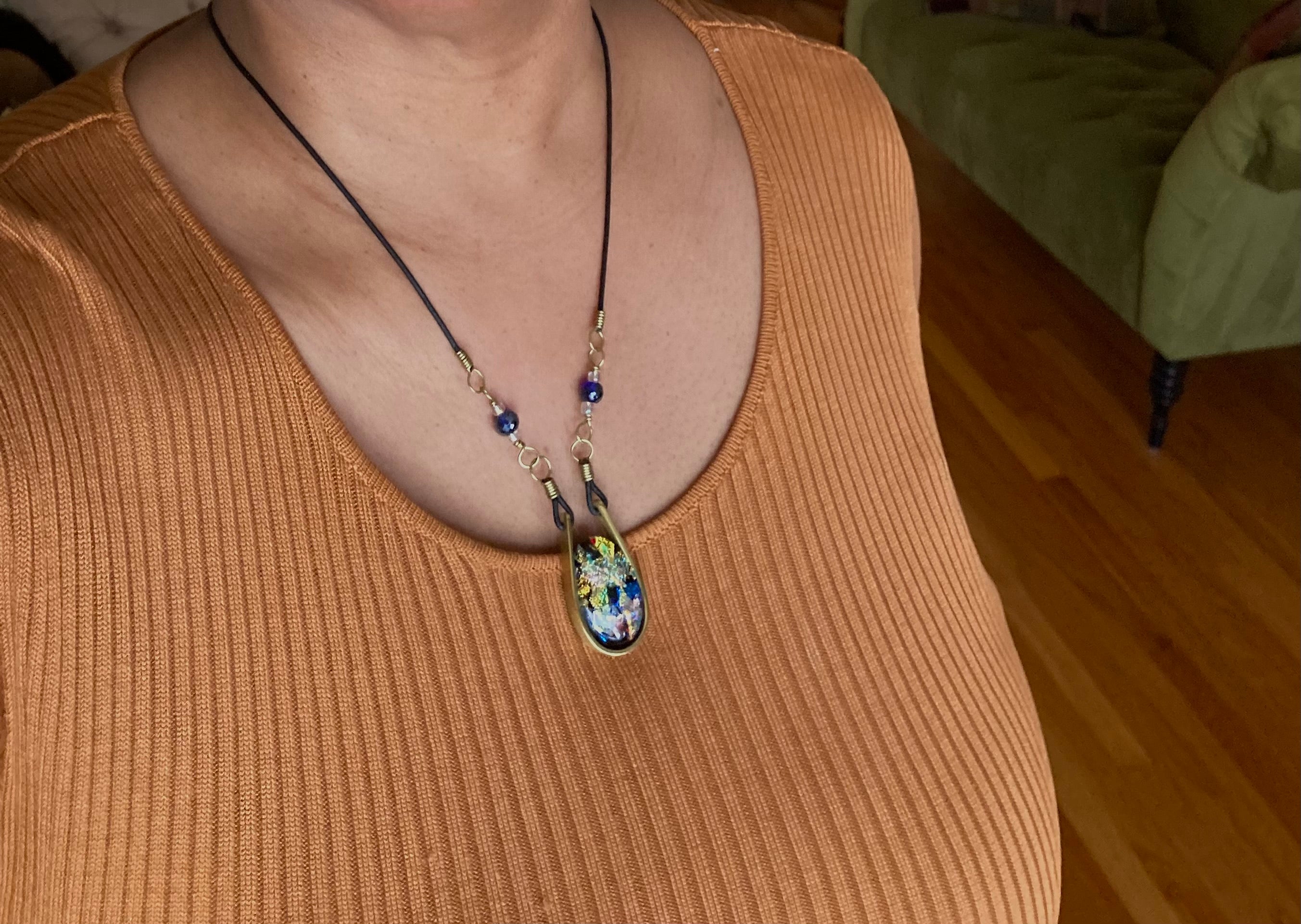 Model wearing modern fused dichroic glass and brass pendant with a beaded leather cord, by 3D Glass Designs.