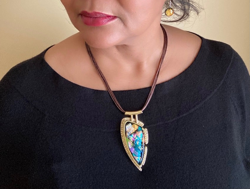 Model wearing contemporary multicolor dichroic glass and brass pendant on a multistrand leather cord, by 3D Glass Designs.