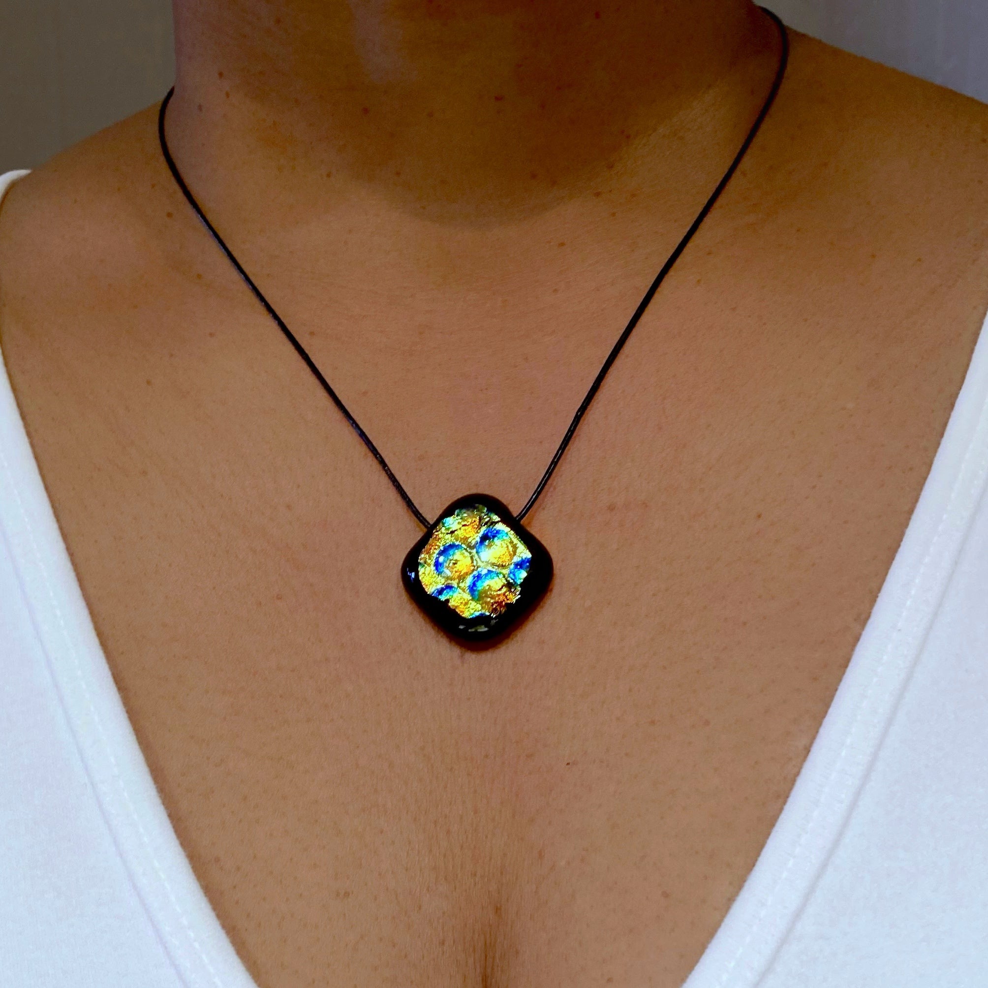 Model wearing fused glass pendant with a white top, b 3D Glass Designs.