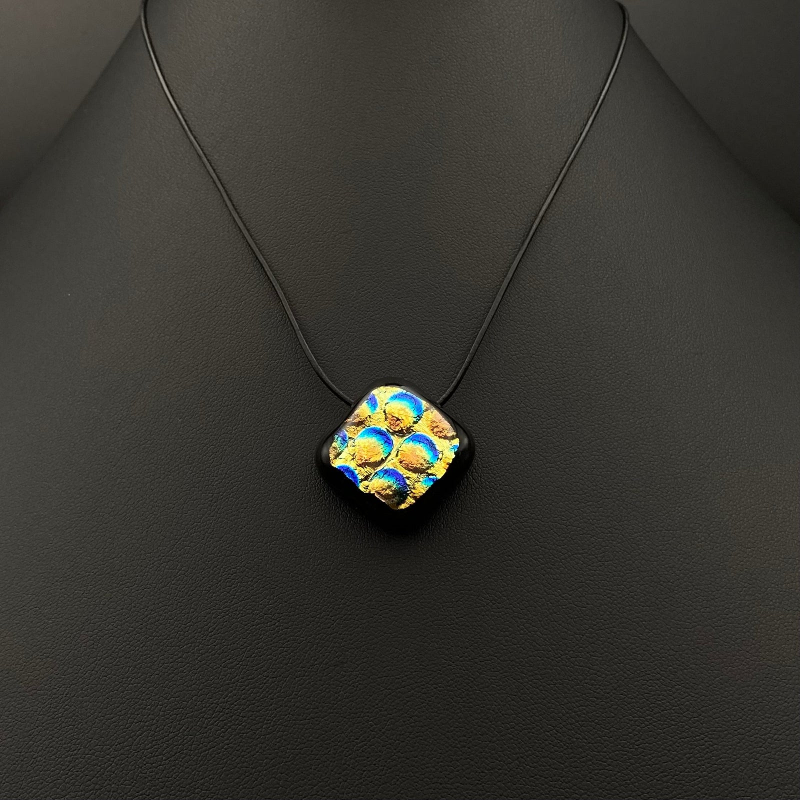 Diamond-shaped fused glass pendant on a thin black leather cord against a black background, by 3D Glass Designs.