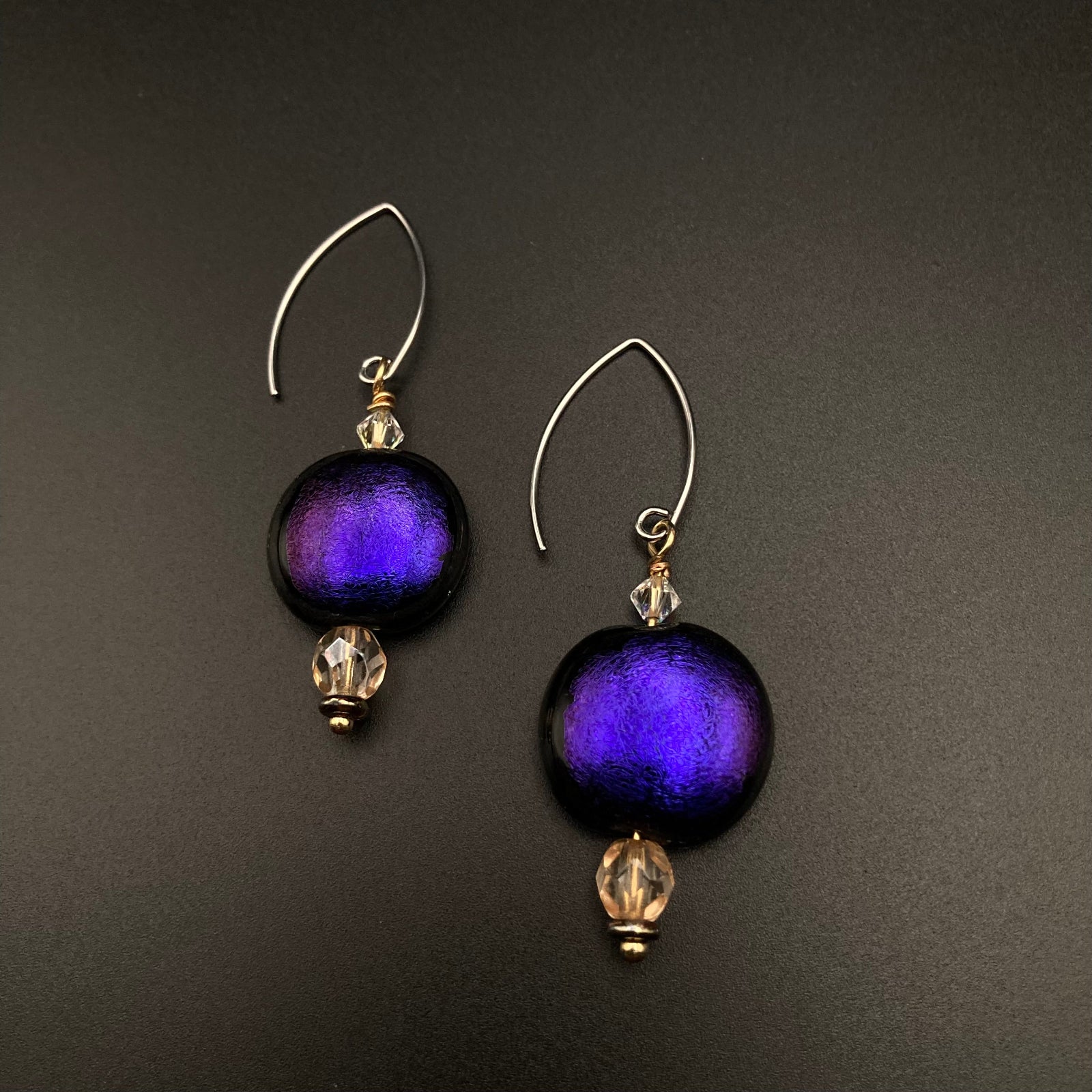 A pair of handmade purple glass earrings with silver-tone ear wires, by 3D Glass Designs.