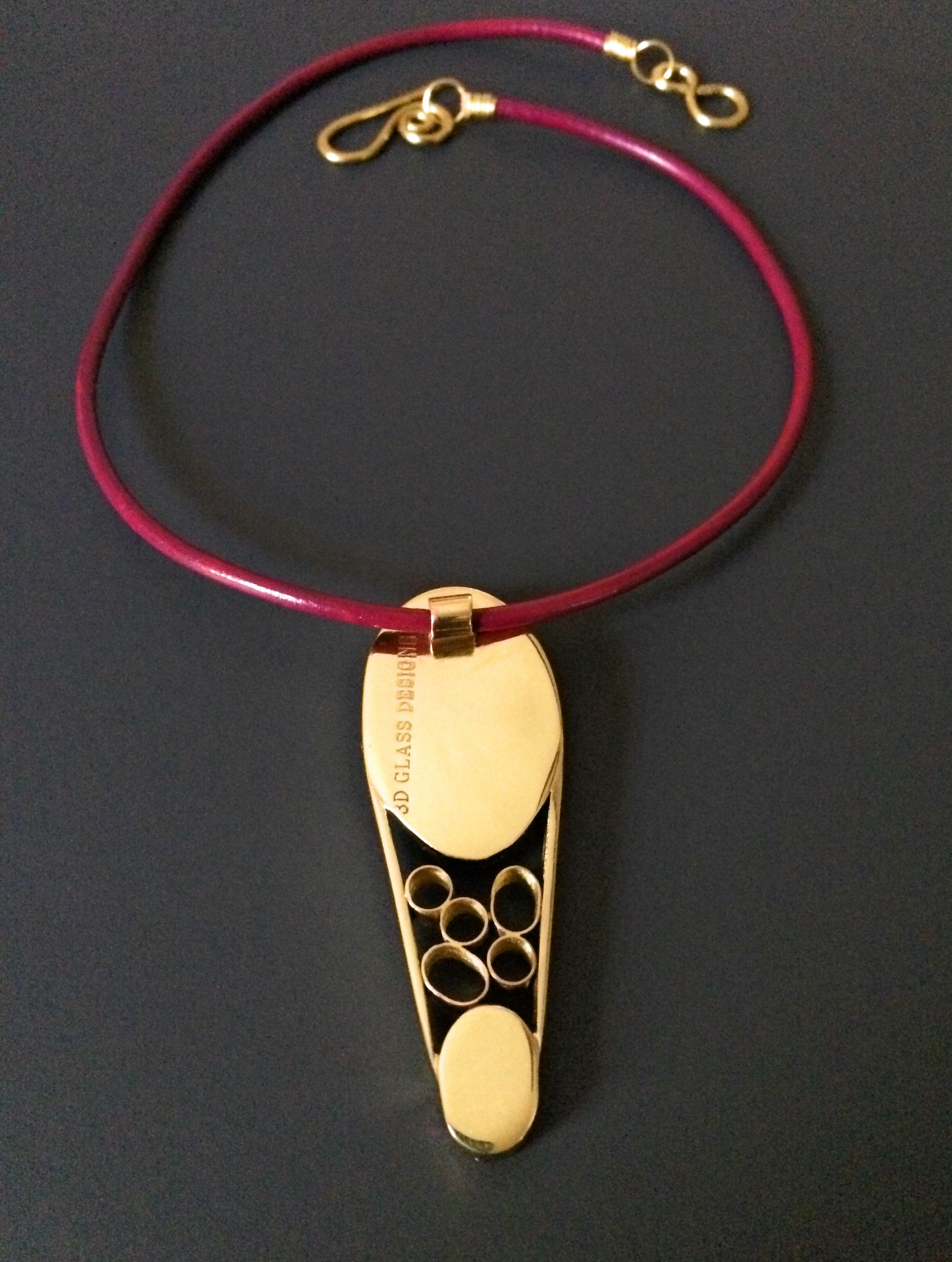 Back side of contemporary dichroic glass and bass pendant with burgundy leather cord, handmade by 3D Glass Designs.