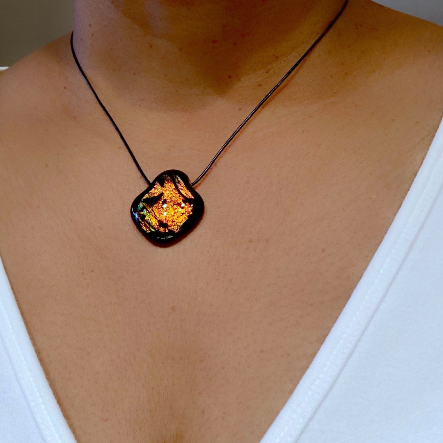 Model wearing orange and black pendant on a black leather cord, by 3D Glass Designs.