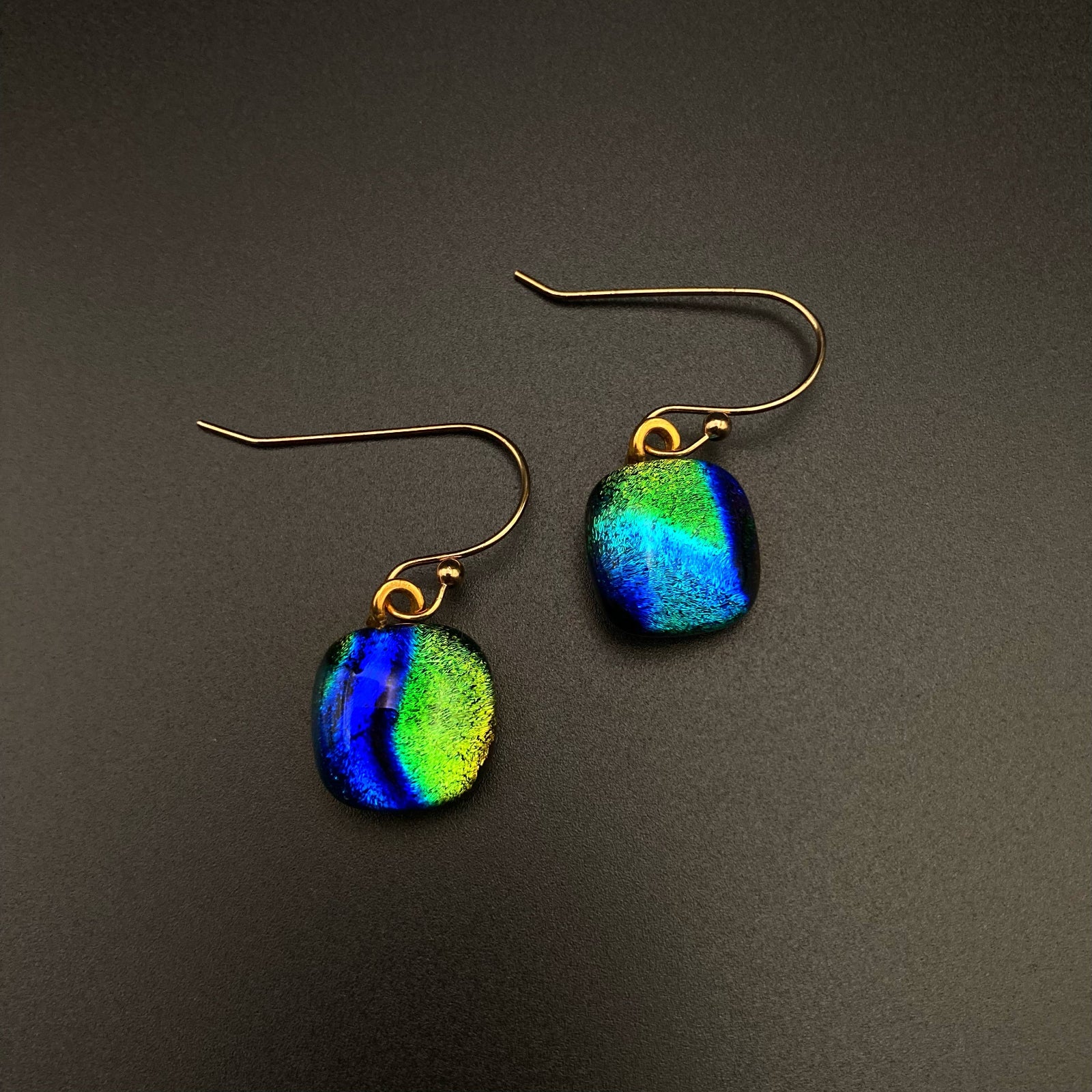 A pair of pierced earrings with blue-green glass dangles, by 3D Glass Designs.