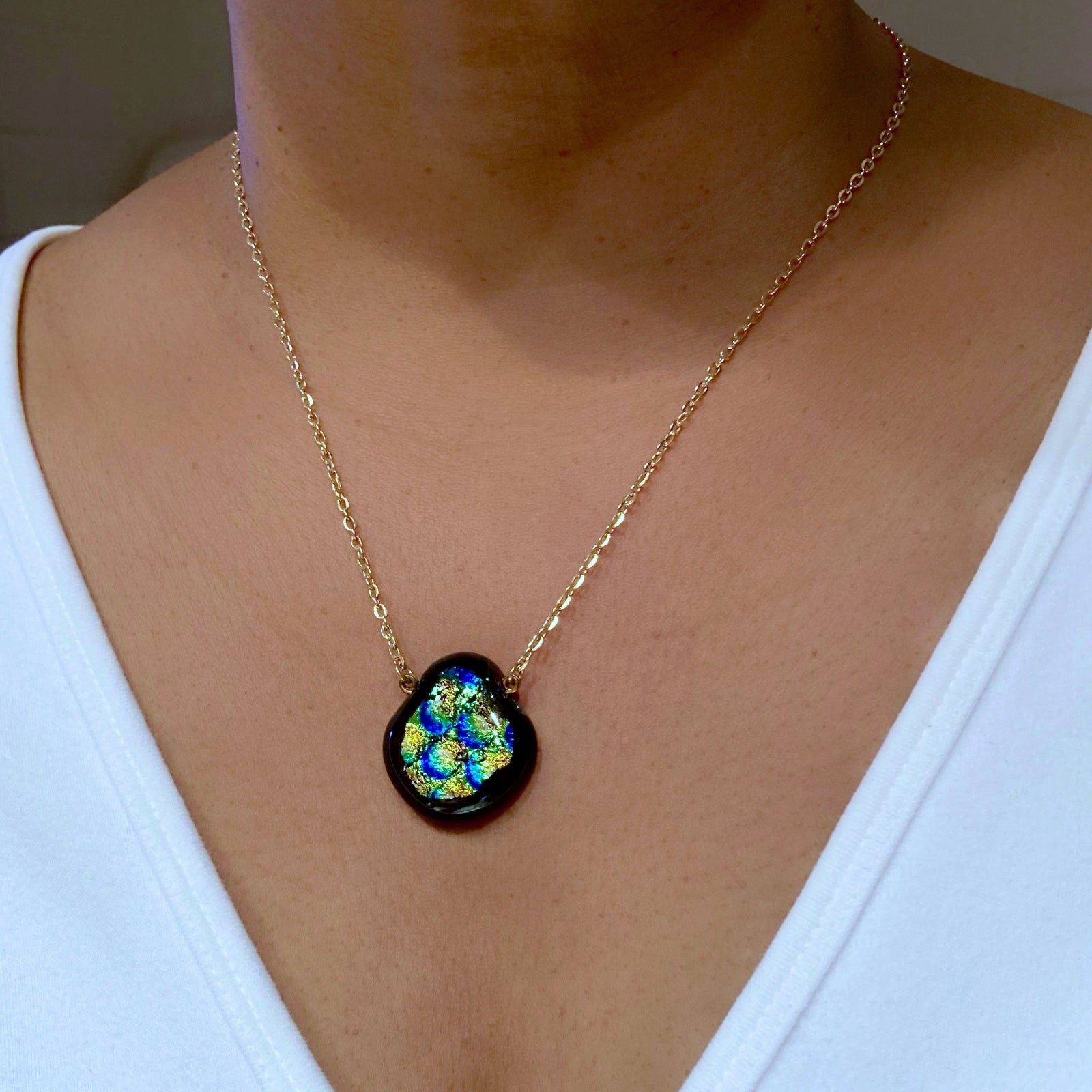 Model wearing dichroic glass pendant on a delicate gold chain, by 3D Glass Designs.