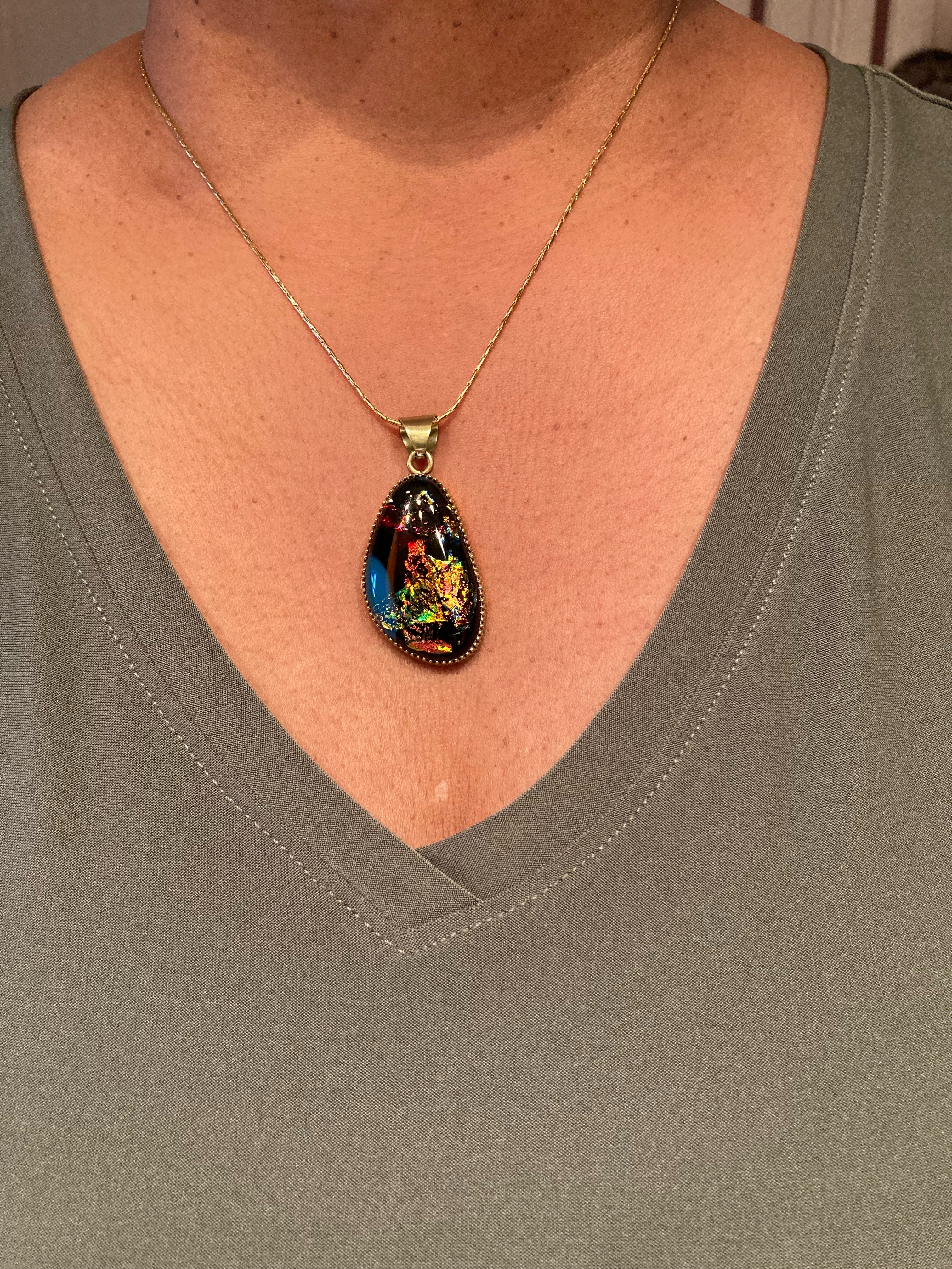Model wearing small colorful dichroic glass pendant set in brass, by 3D Glass Designs.