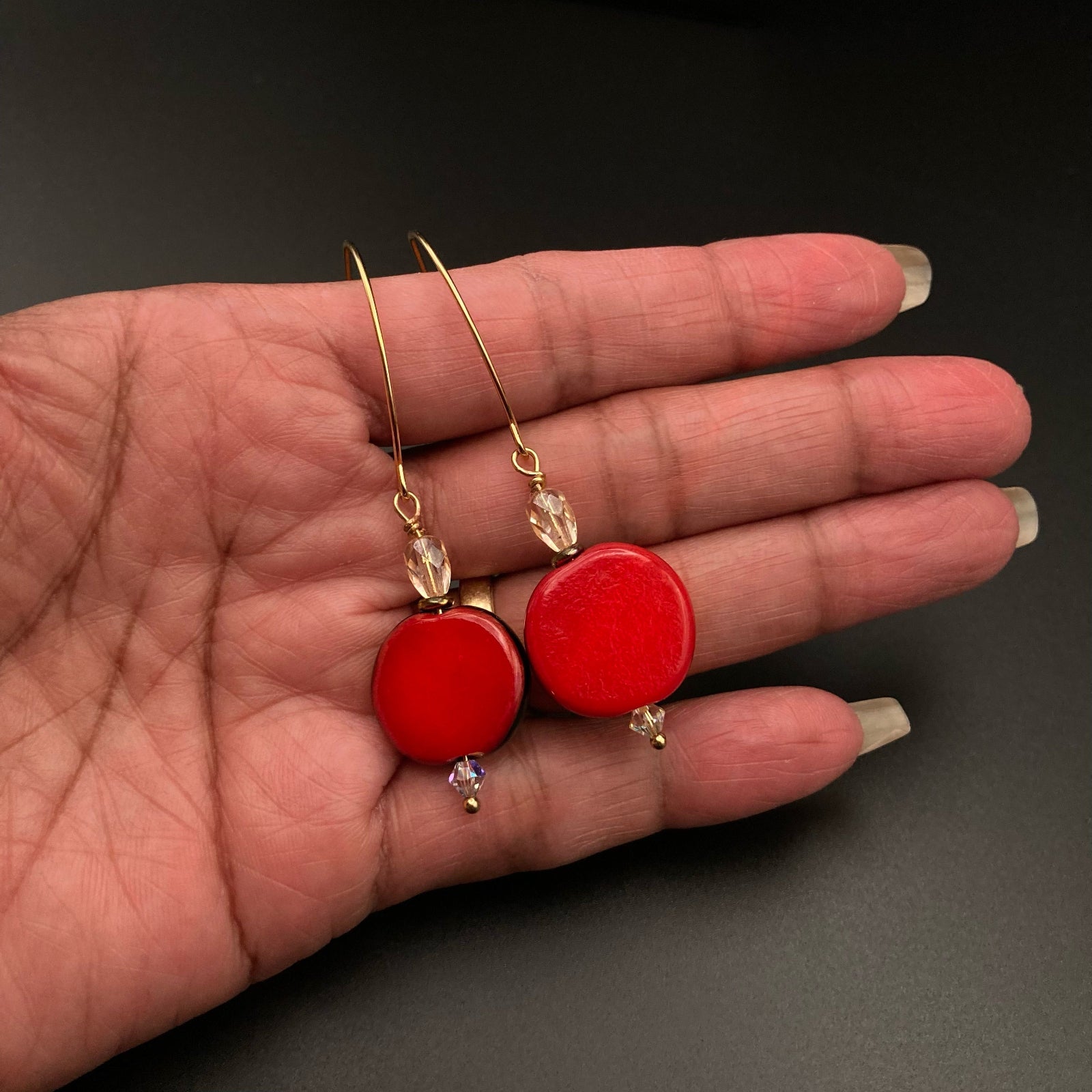 Hand holding red fused glass earrings, by 3D Glass Designs.
