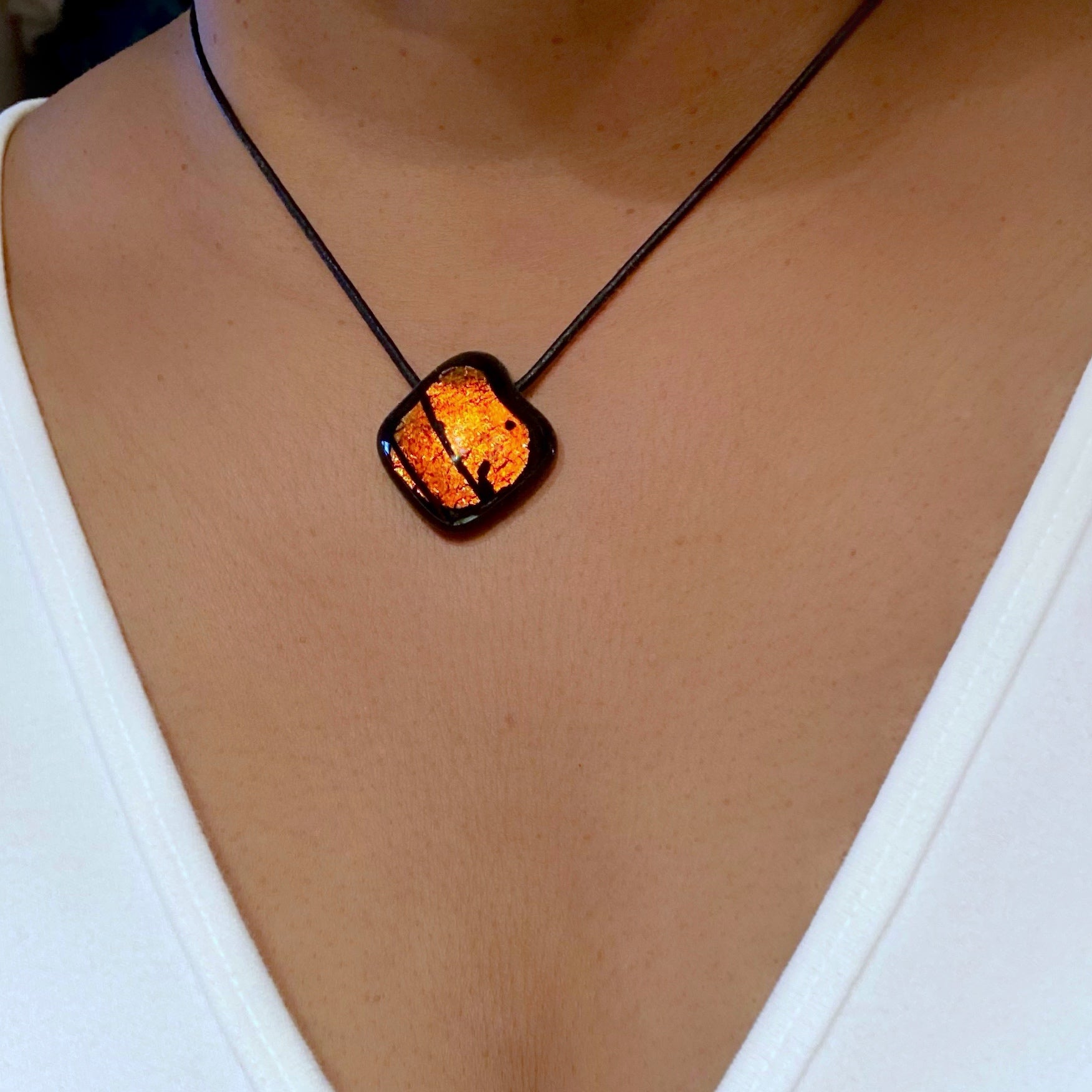 Model wearing orange and black fused glass pendant on a black leather cord, by 3D Glass Designs.