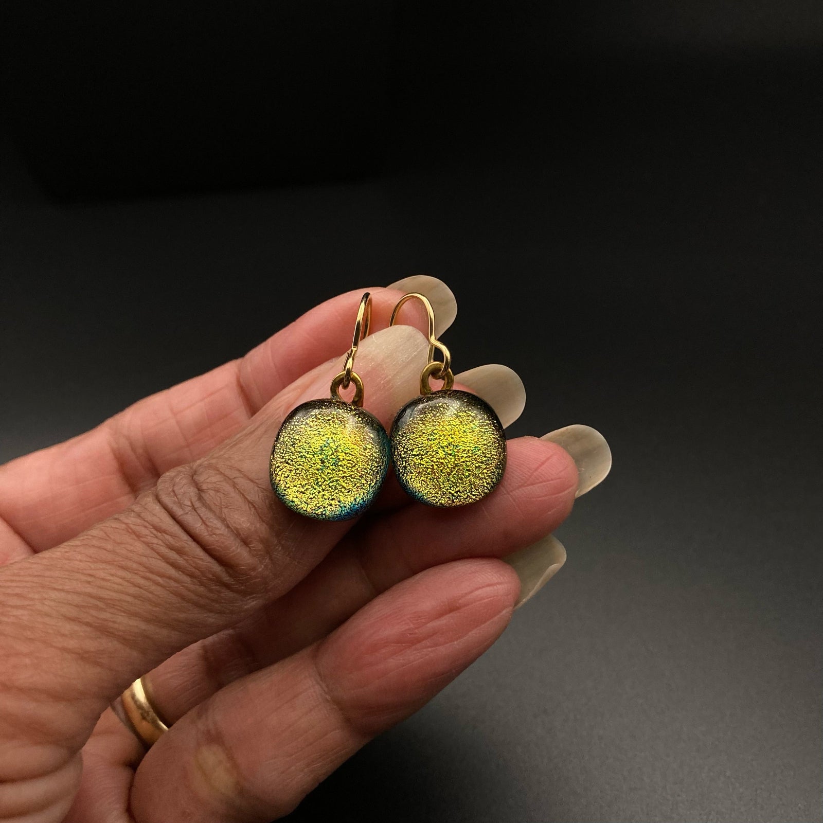 Hand holding a pair of glass earrings, by 3D Glass Designs.