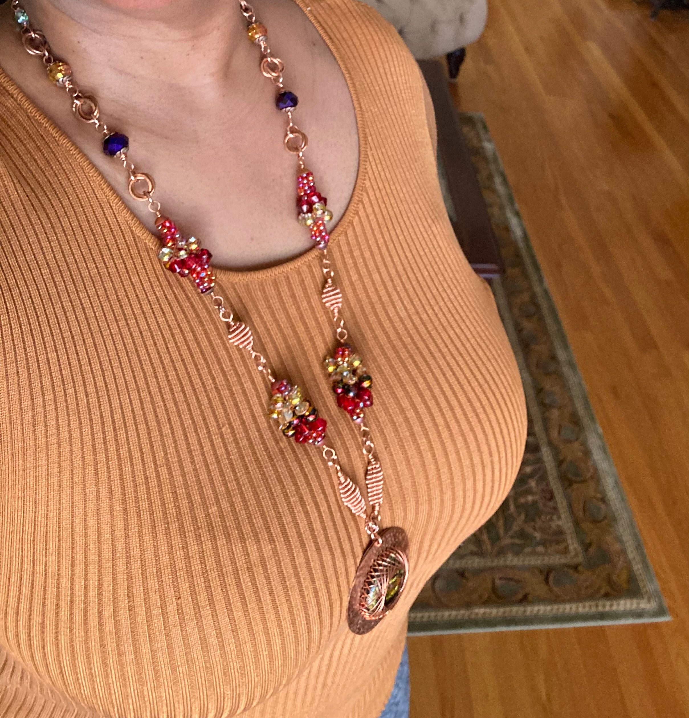 Model wearing long copper and dichroic glass pendant necklace with handmade bead clusters, by 3D Glass Designs.