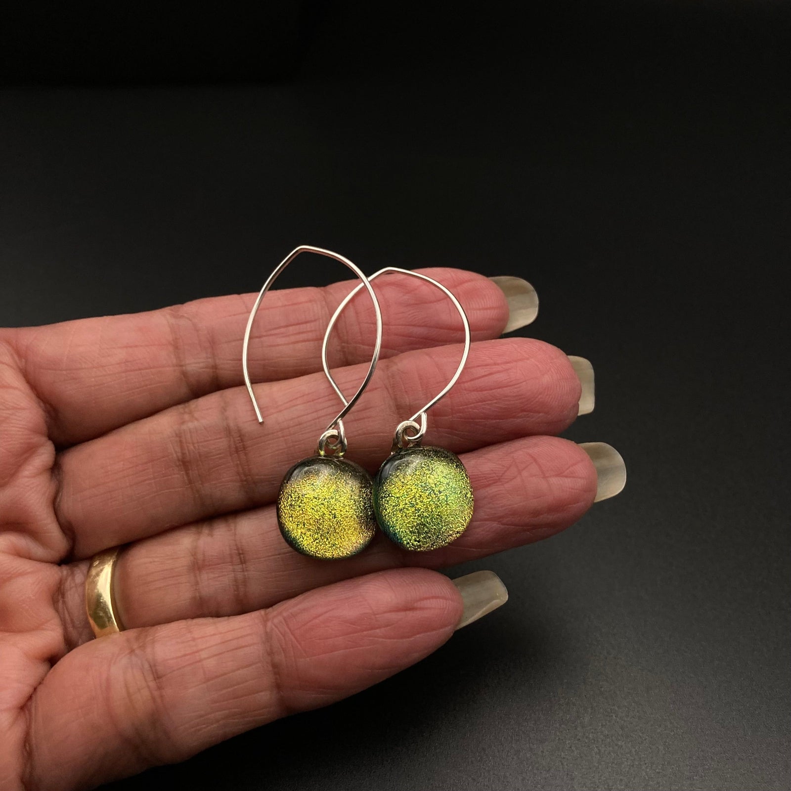 Hand holding a pair of yellow glass dangle earrings, by 3D Glass Designs.