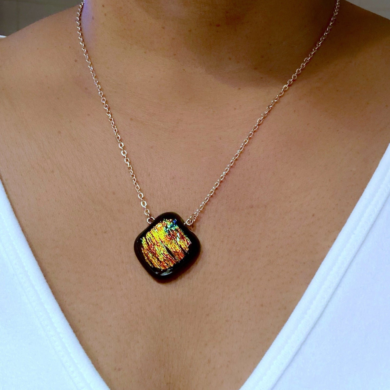 Model wearing an orange fused glass pendant on a gold chain, by 3D Glass Designs.