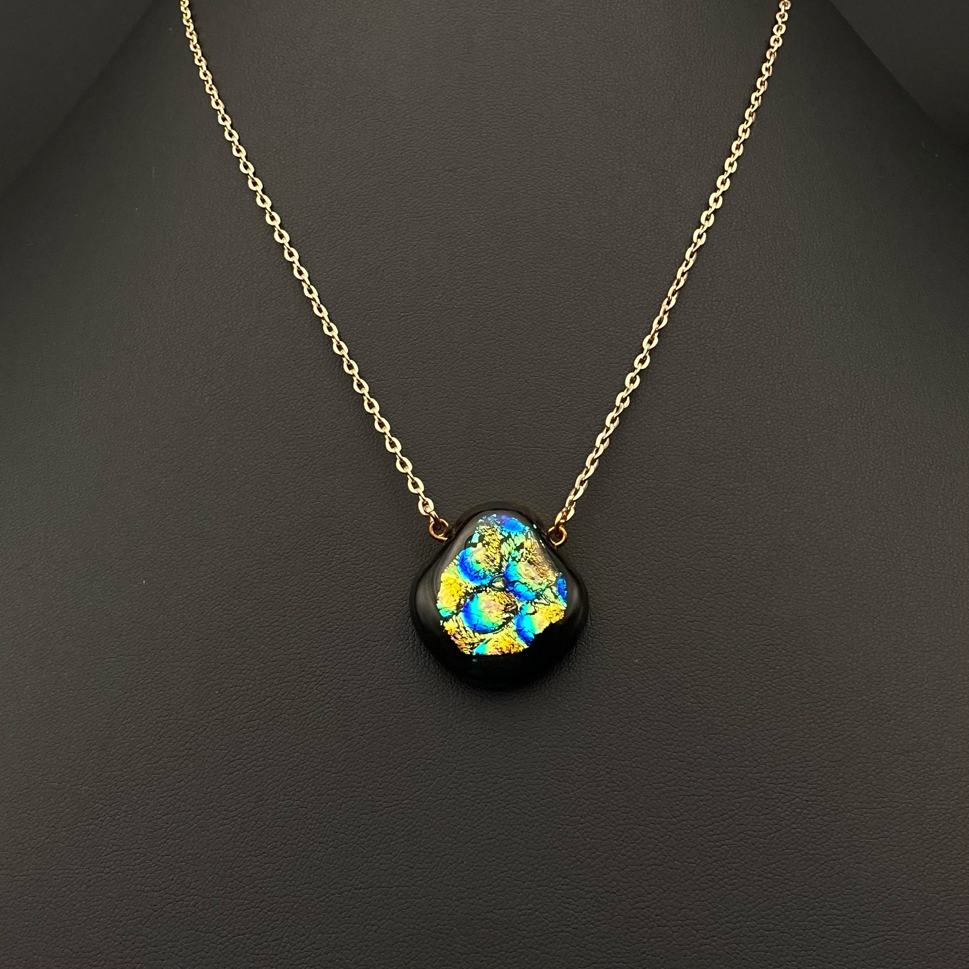 Fused glass pendant on a delicate gold chain against a black background, by 3D Glass Designs.