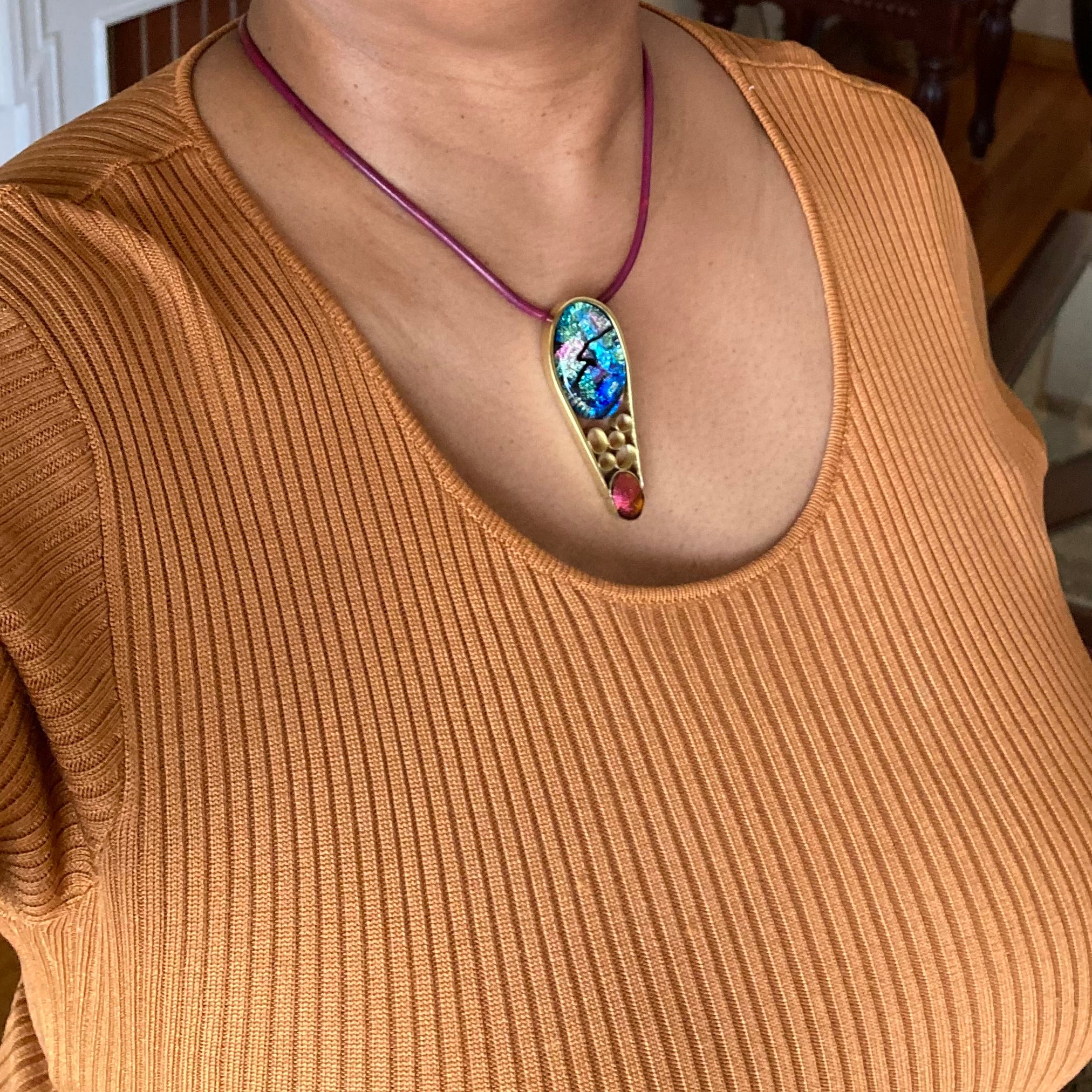 Model wearing contemporary dichroic glass and bass pendant, handmade by 3D Glass Designs.