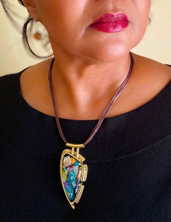 Model wearing contemporary multicolor dichroic glass and brass pendant on a multistrand leather cord, by 3D Glass Designs.