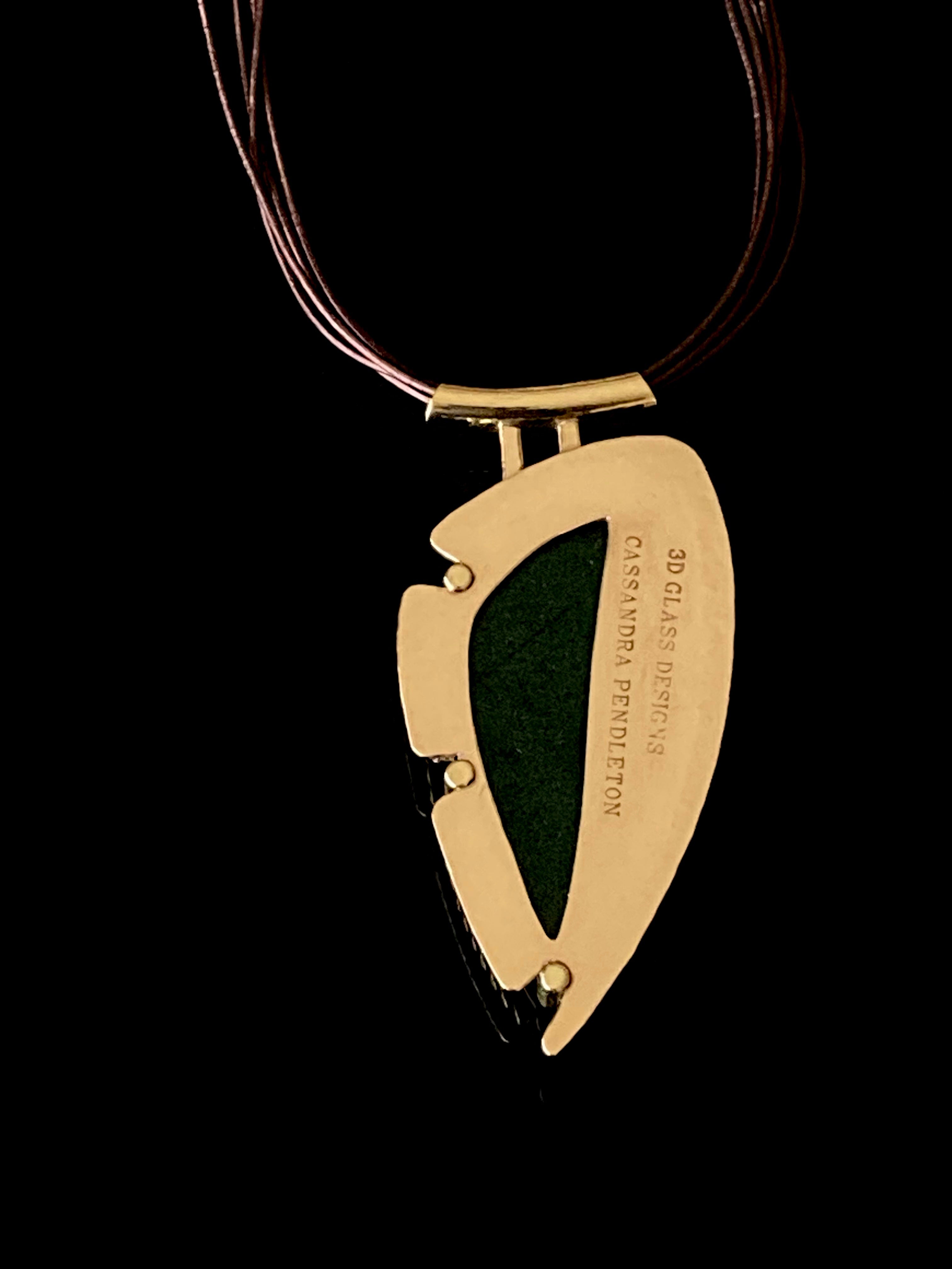 Handcrafted brass pendant featuring multicolored dichroic glass in a shield-shape hung on a multistrand leather necklace, by 3D Glass Designs.