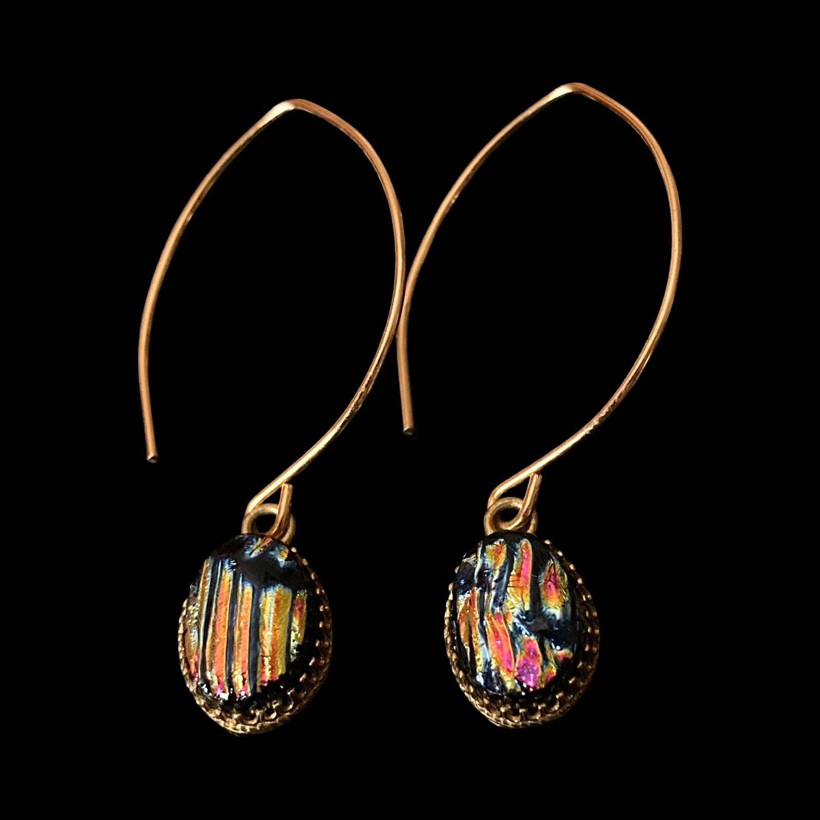 Pair of earrings with colorful striped design on a black background, by 3D Glass Designs.