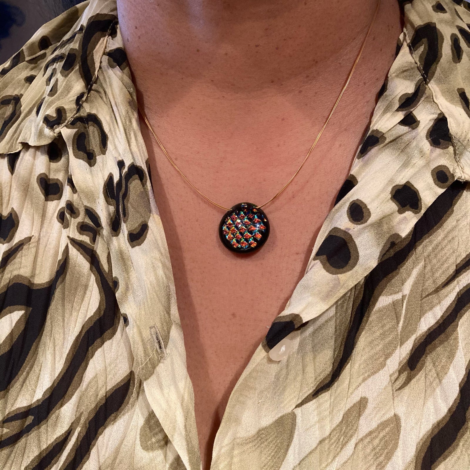 Model wearing multi-colored fused glass pendant on gold beading wire, by 3D Glass Designs.
