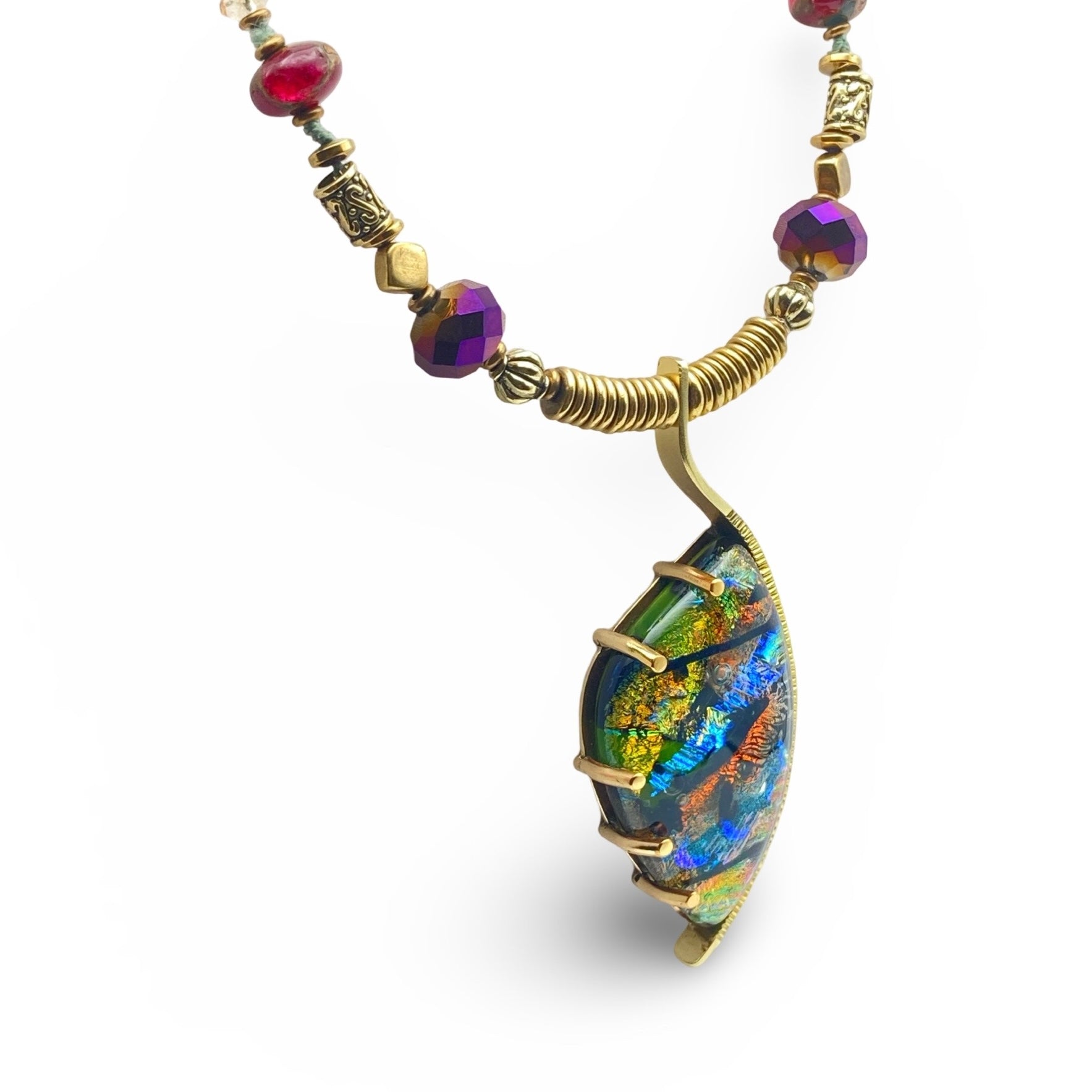 Dichroic glass set in a unique brass pendant, with prongs on left side and a textured bezel on the right side. Pendant is hung on a 29" long hand-knotted multicolor beaded necklace, by 3D Glass Designs.