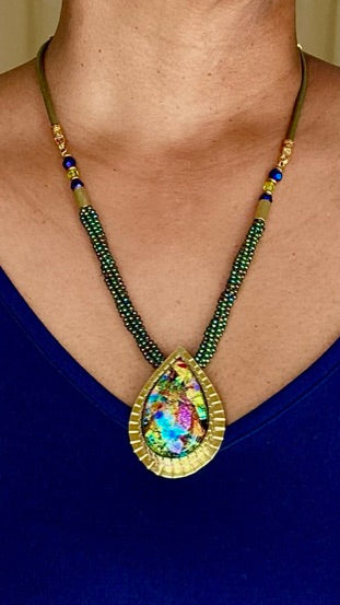Model wearing handcrafted fused glass pendant set in a custom-made brass setting, with a beaded leather necklace. By 3D Glass Designs.