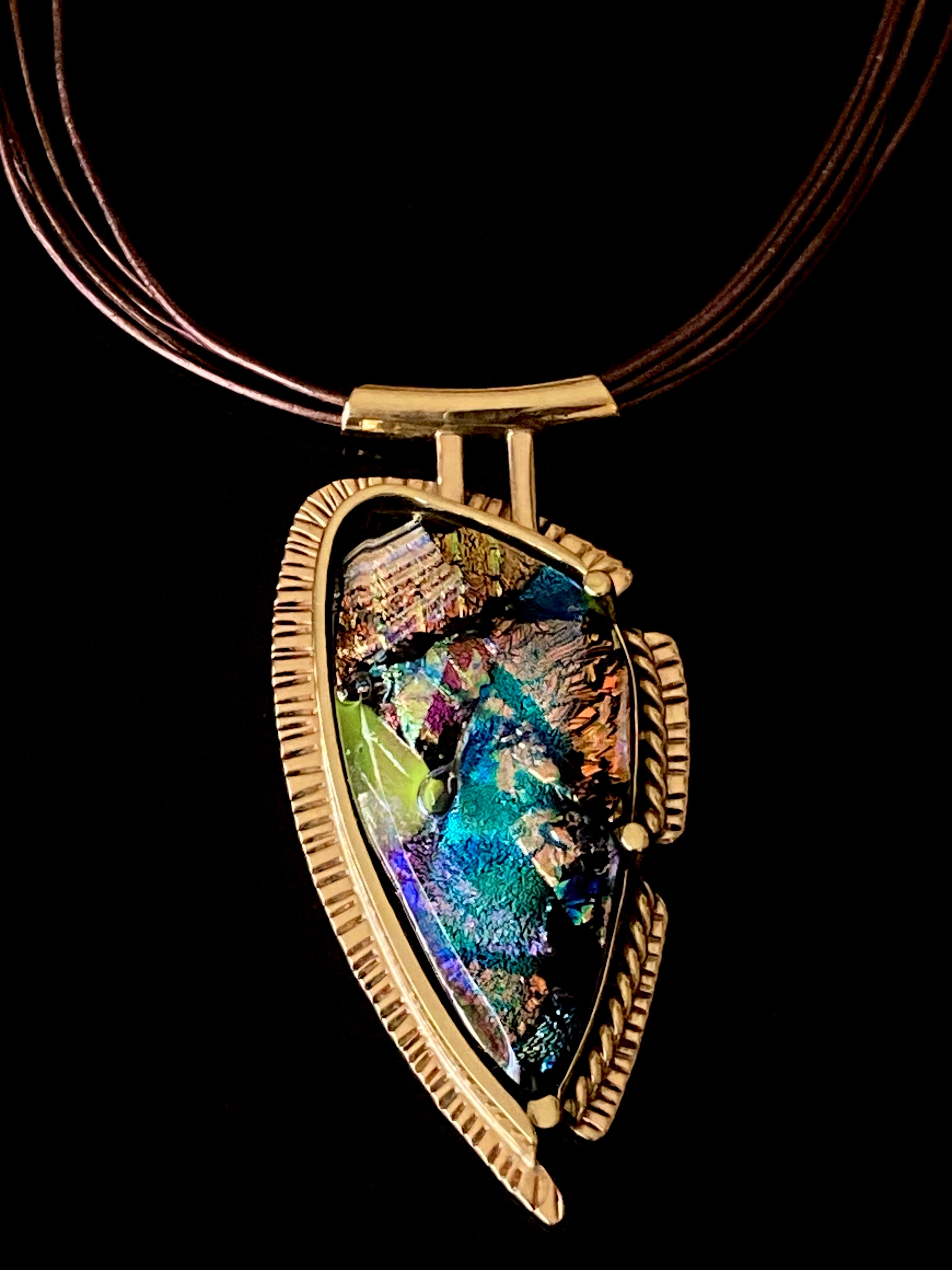 Handcrafted brass pendant featuring multicolored dichroic glass in a shield-shape hung on a multistrand leather necklace, by 3D Glass Designs.