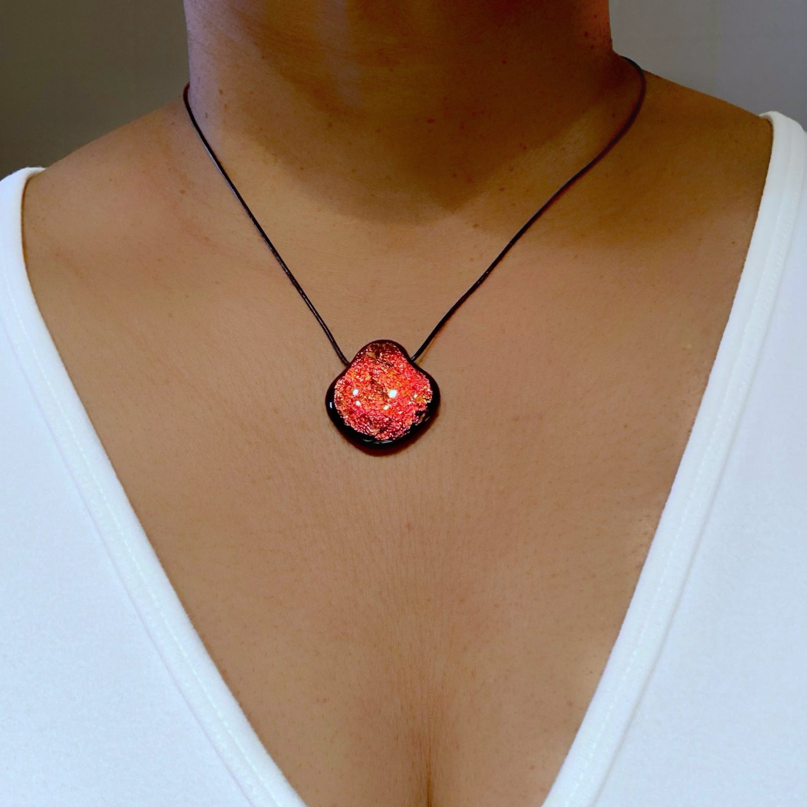 Model wearing a red glass pendant on a black leather cord with a white tee shirt, by 3D Glass Designs.