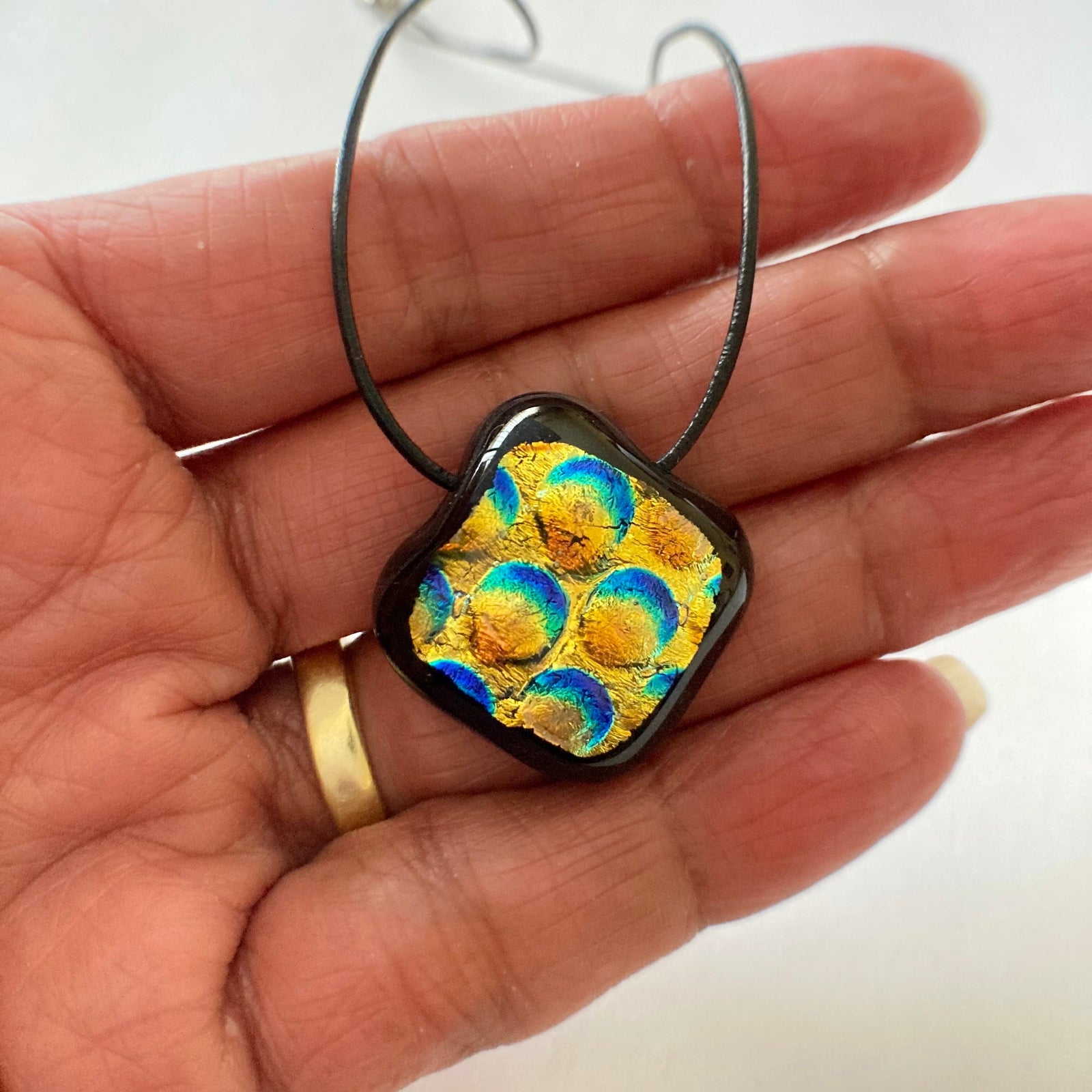 Hand holding small, fused glass pendant, by 3D lass Design.