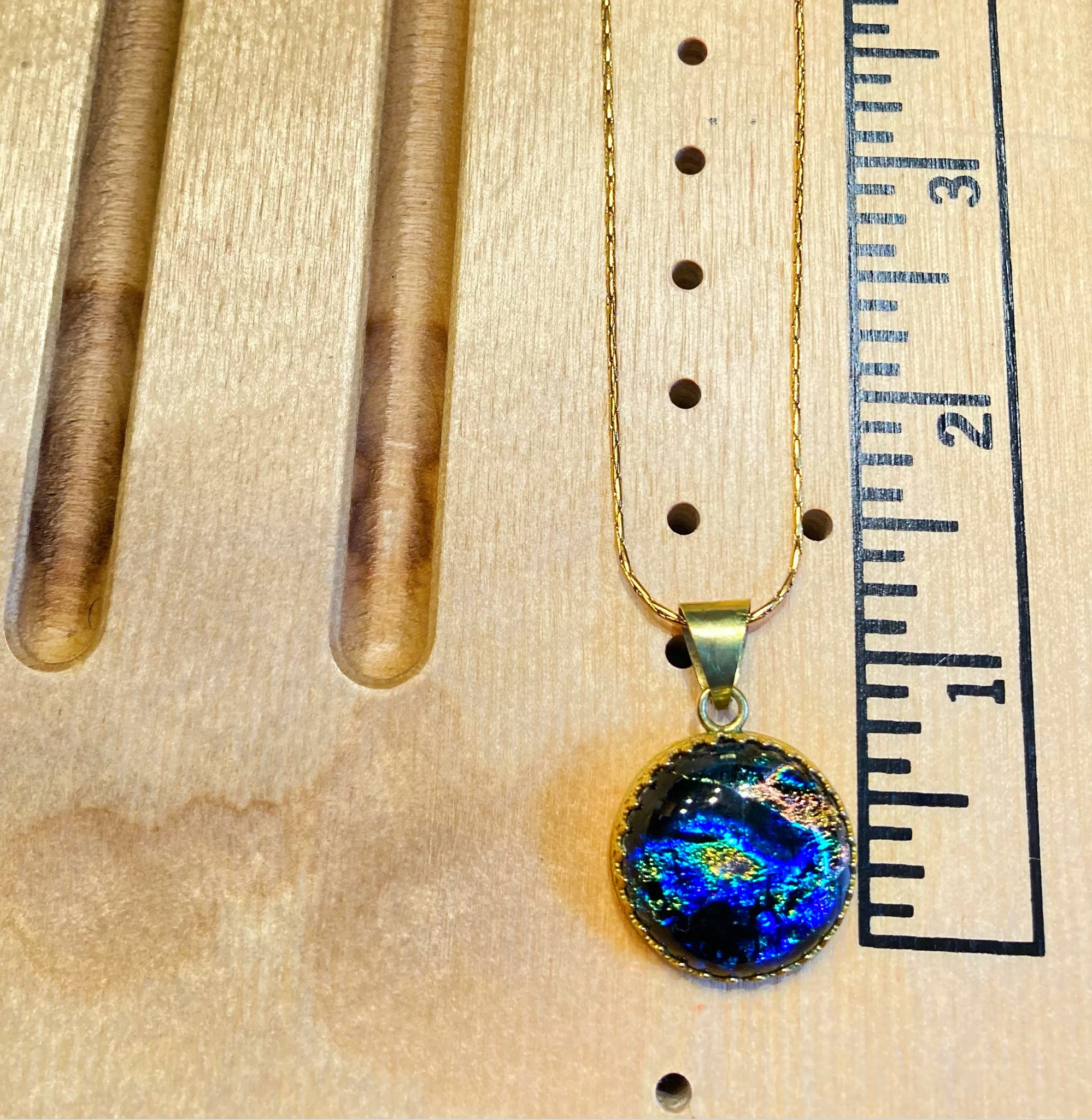 Small round fused glass pendant on a wooden measuring board, By 3D Glass Designs.