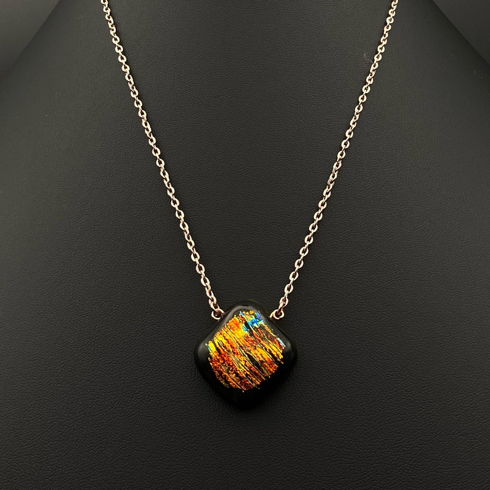 Orange dichroic glass pendant on a gold chain against a black background, by 3D Glass Designs.