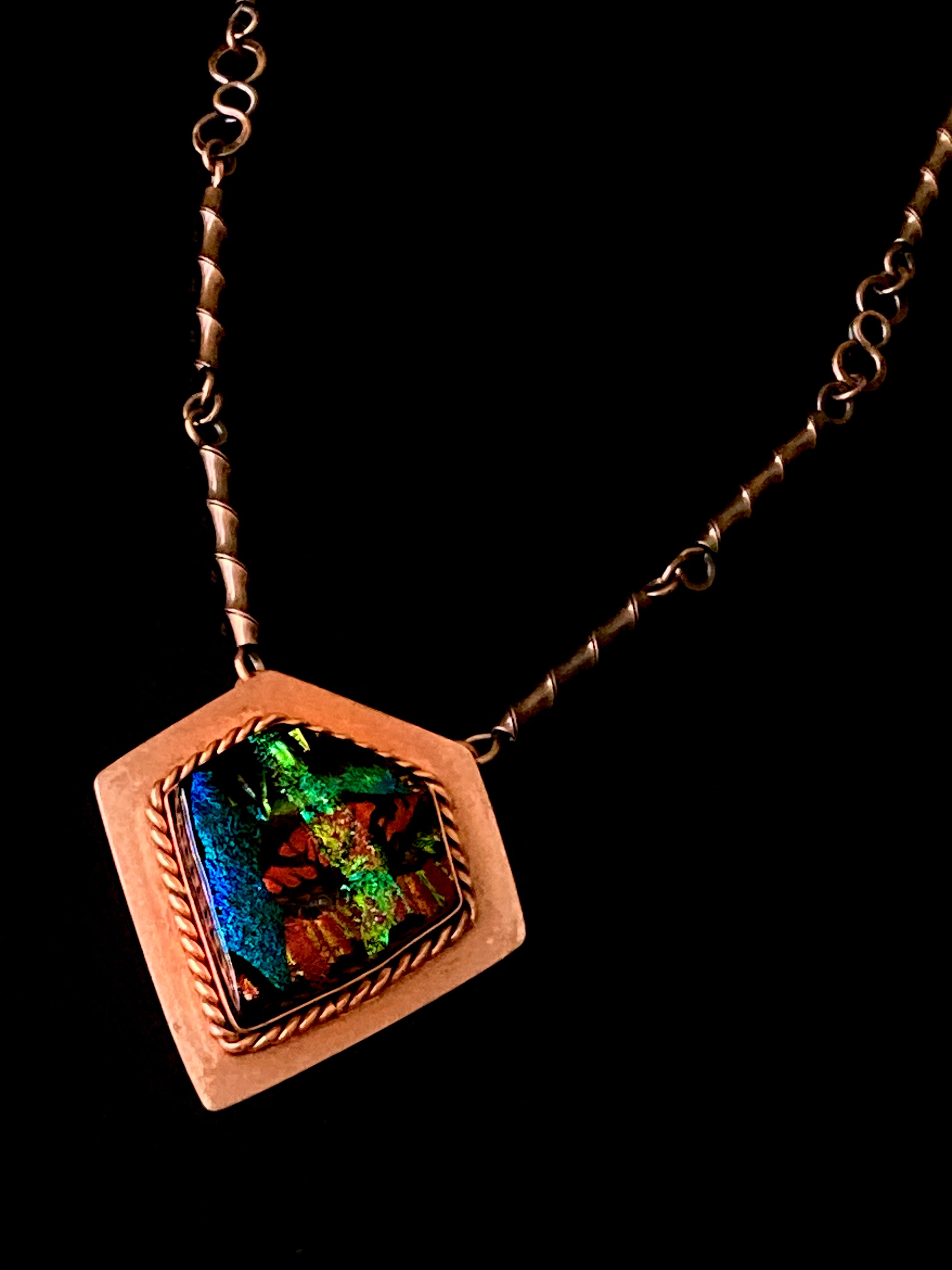 Stunning unisex fused glass and copper pendant necklace by 3D Glass Designs. Dichroic glass in blue, green and rust hues set in a handcrafted diamond-shaped shield copper pendant with an elegant rope detail surrounding the bezel. The handmade copper necklace consists of twisted copper links that resembles bamboo and a handmade clasp.