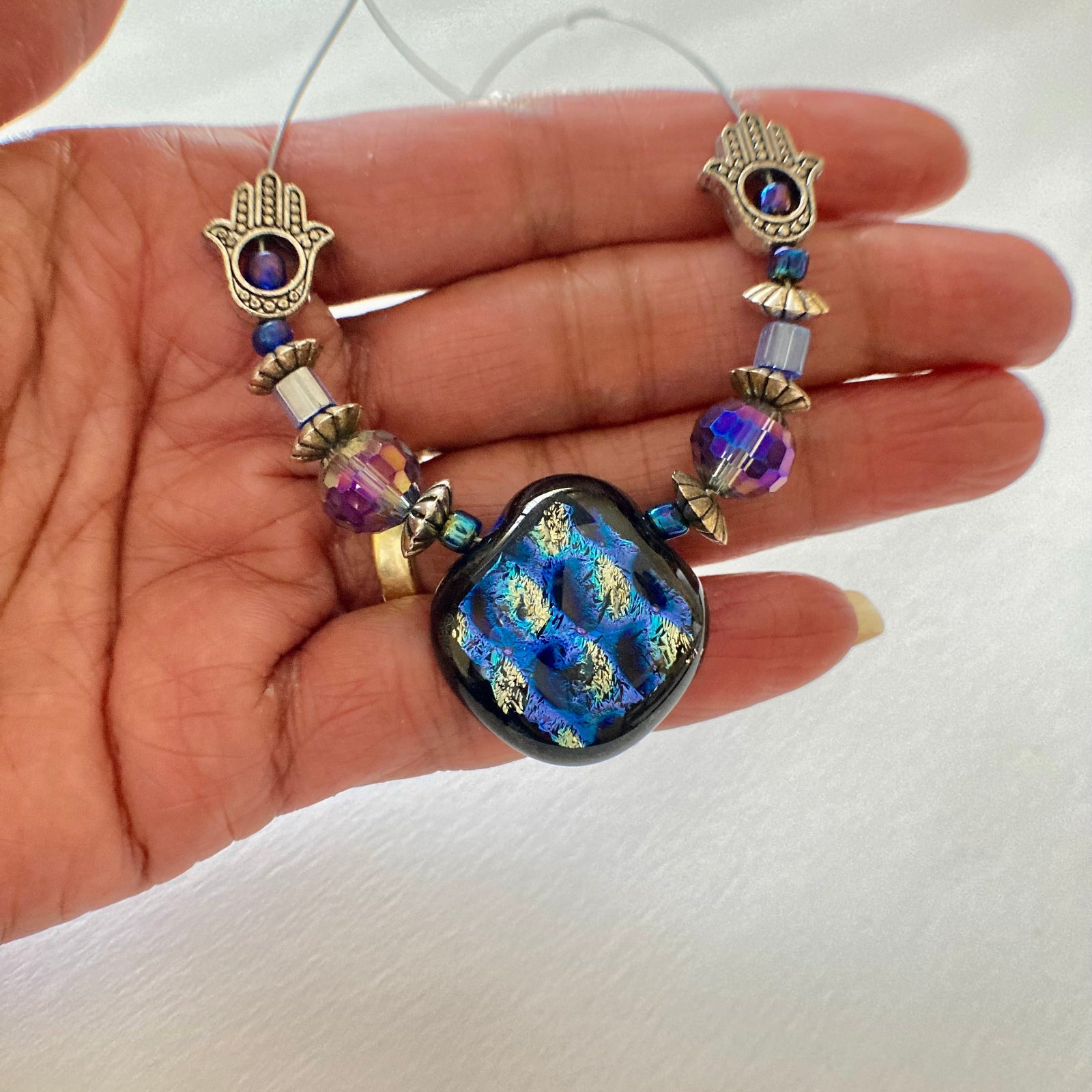 Hand holding beaded glass pendant necklace, by 3D Glass Designs.