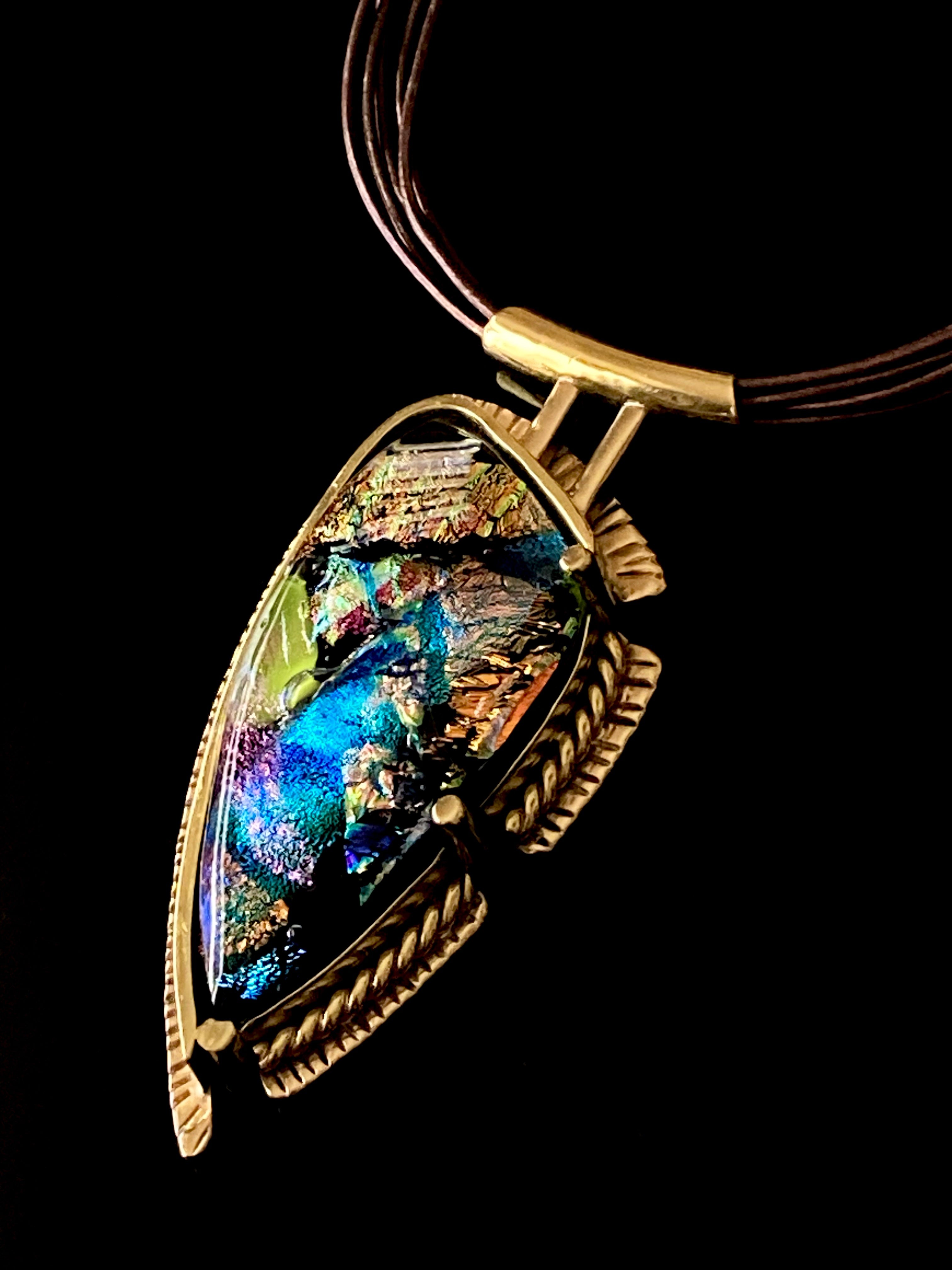 Handcrafted brass pendant featuring multicolored dichroic glass in a shield-shape hung on a multistrand leather necklace, by 3D Glass Designs.
