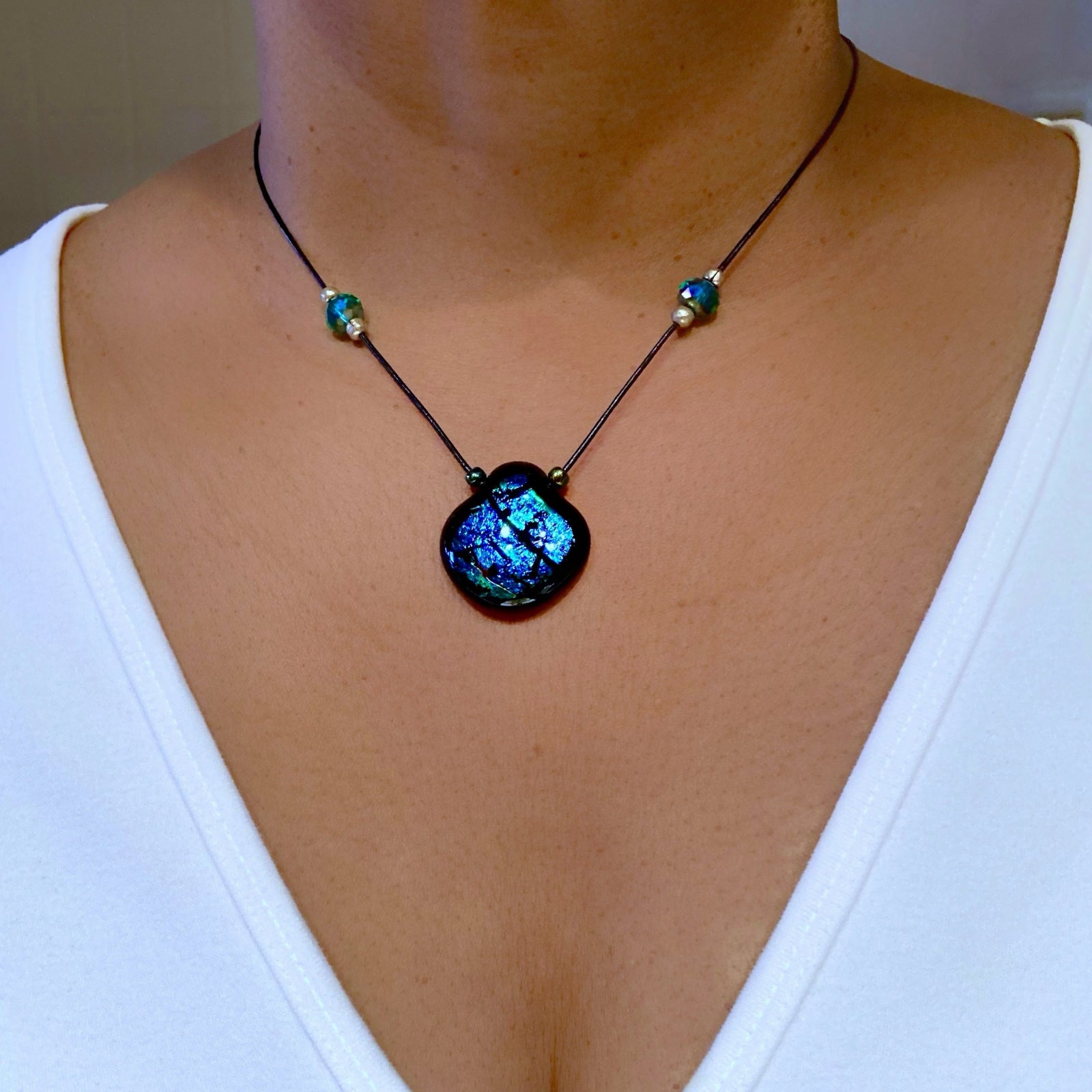 Model wearing blue-green glass pendant on a beaded black leather cord, by 3D Glass Designs.