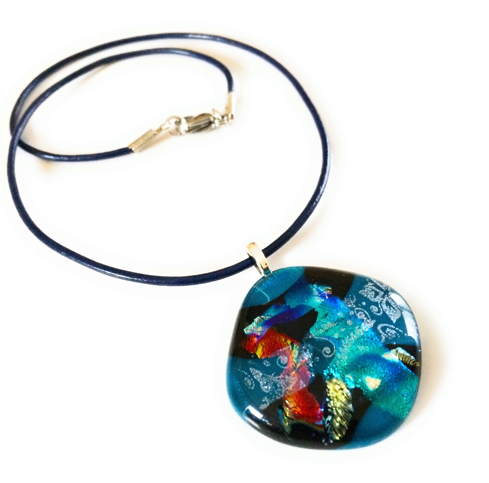 Fused glass pendant in teal, red, silver, blue and gold on a blue 18-inch leather cord, by 3D Glass Designs.