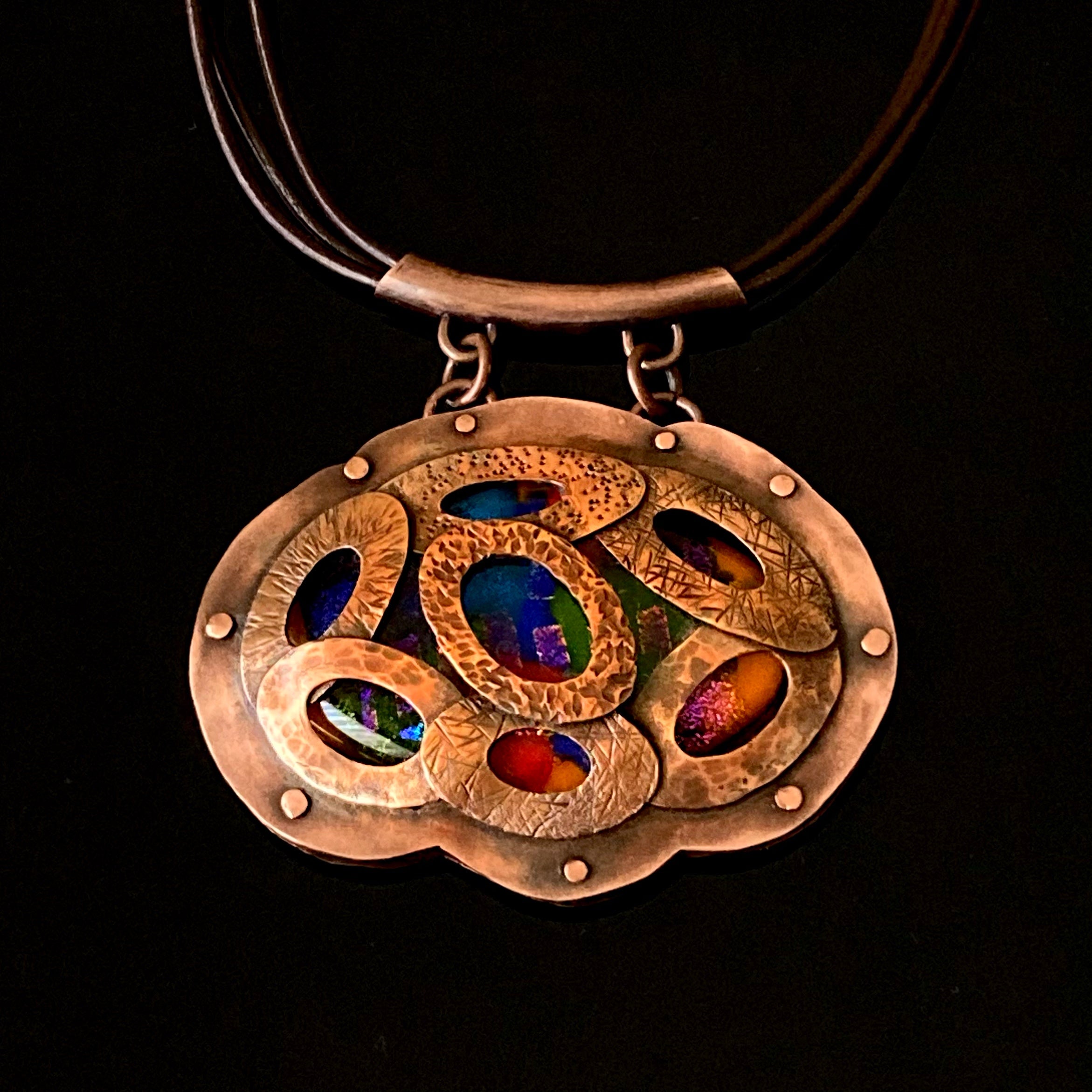 Artisan designed copper and fused glass pendant, oval shaped with overlapping copper ovals on top, revealing colorful glass beneath. By 3D Glass Designs