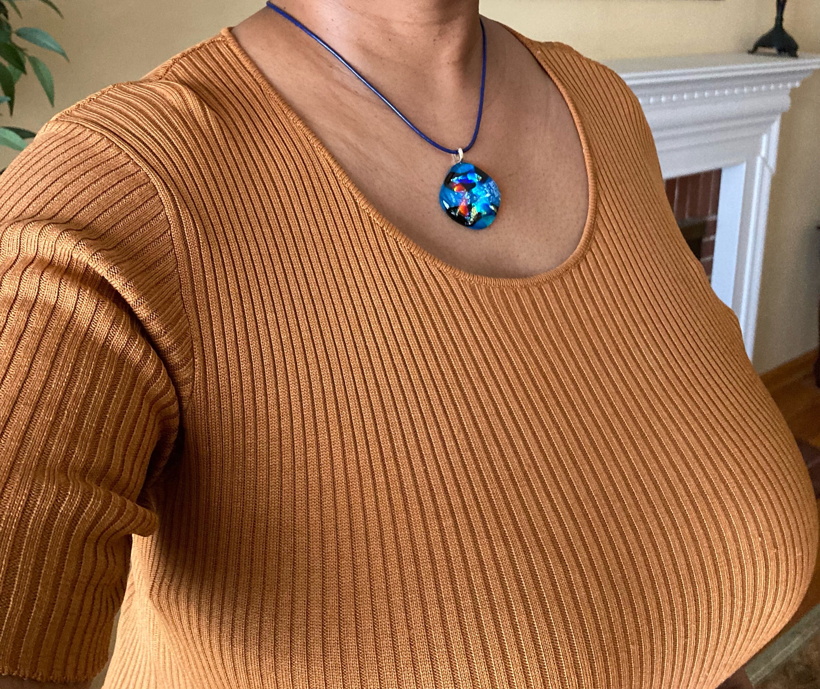 Model wearing fused glass pendant in teal, red, silver, blue and gold on an 18-inch blue leather cord, by 3D Glass Designs.