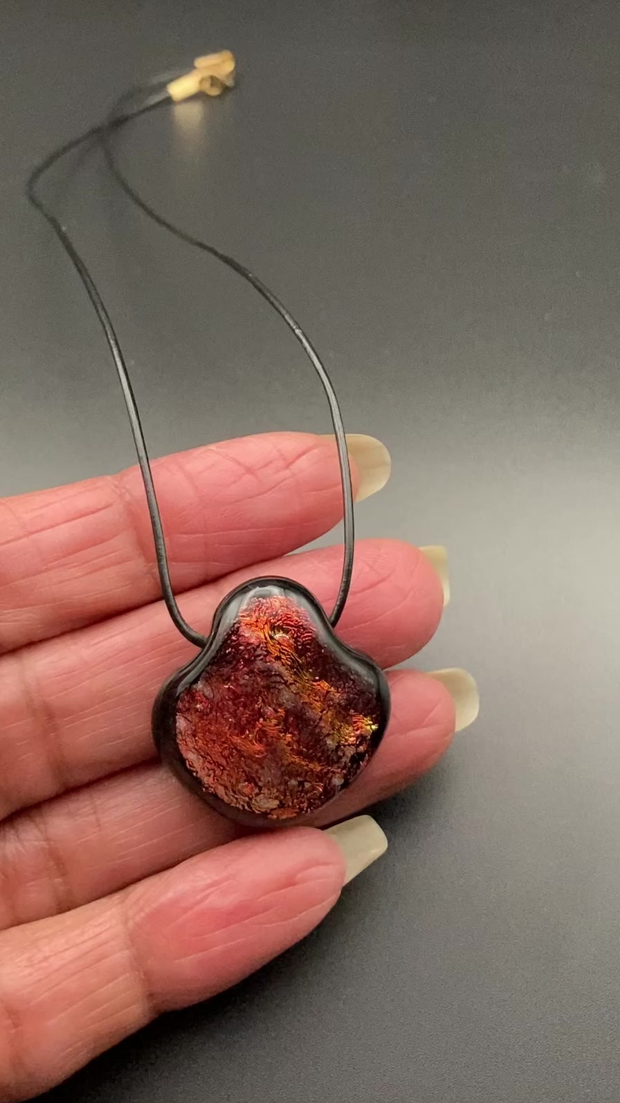 Hand holding red dichroic pendant, by 3D Glass Designs.