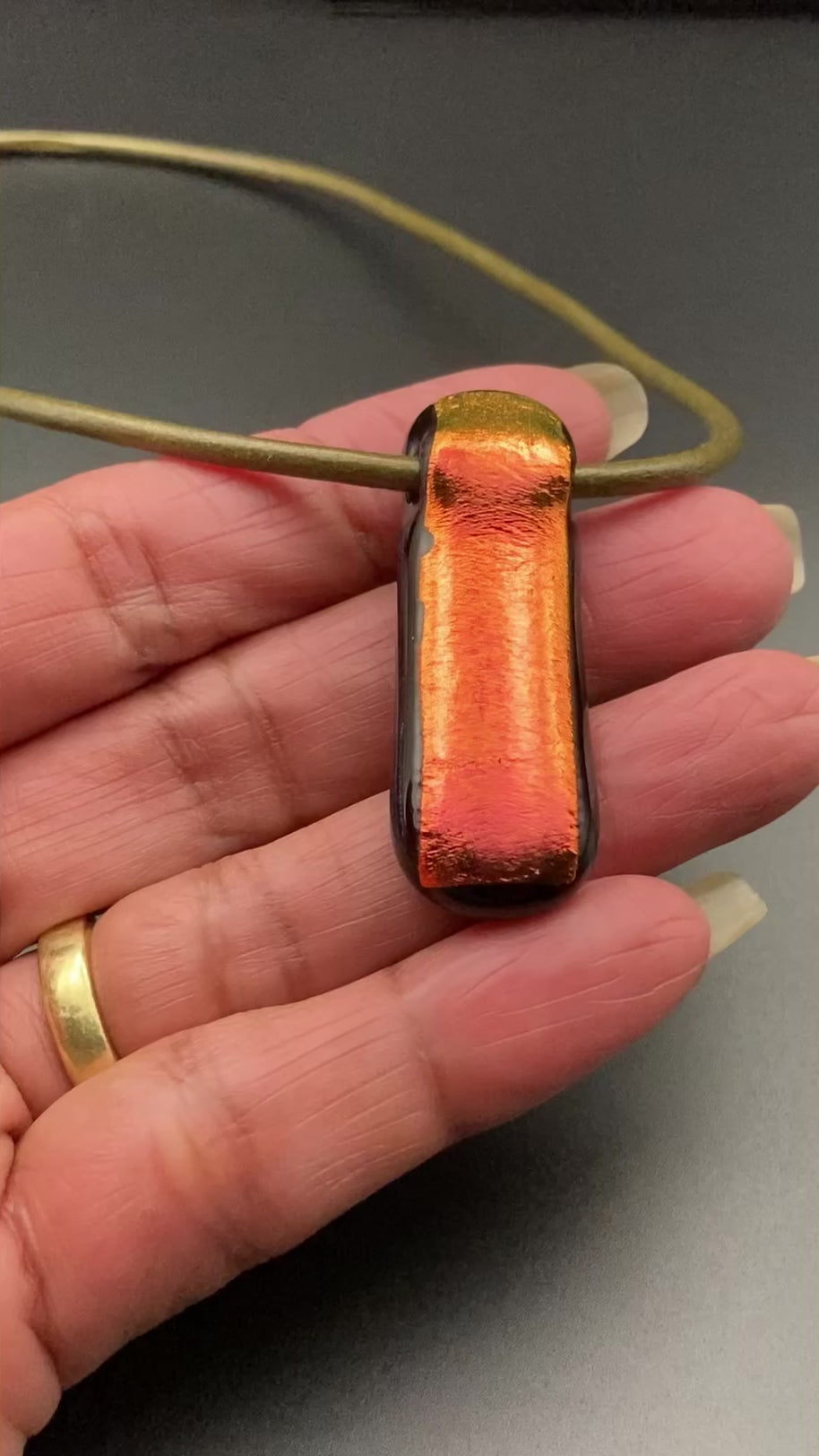 Hand holding red dichroic glass pendant, by 3D Glass Design.