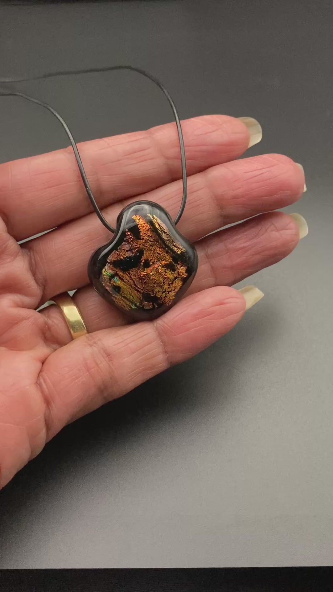 Hand holding orange and black glass pendant, by 3D Glass Designs.