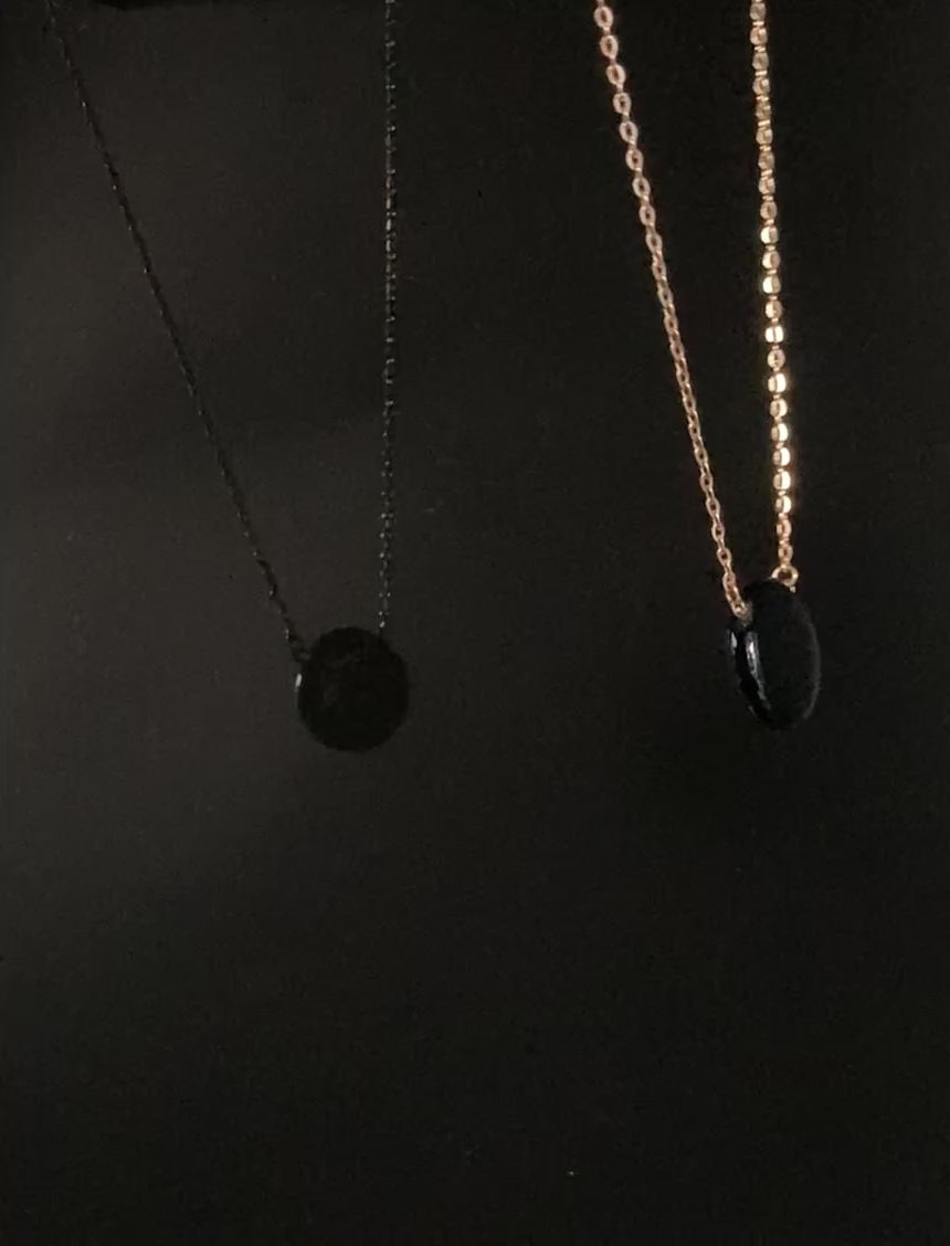 Rotating fused glass pendant on a gold chain against a black background, by 3D Glass Designs.