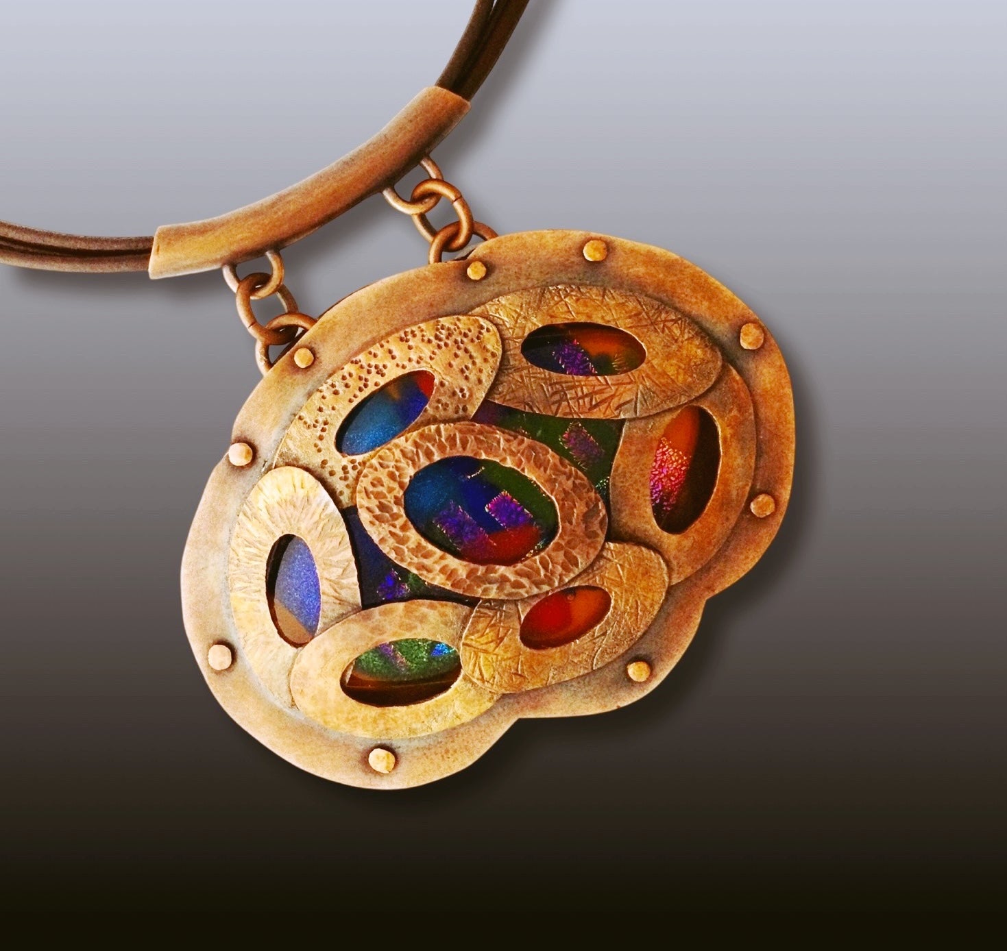 Artisan designed copper and fused glass pendant, oval shaped with overlapping copper ovals on top, revealing colorful glass beneath. By 3D Glass Designs